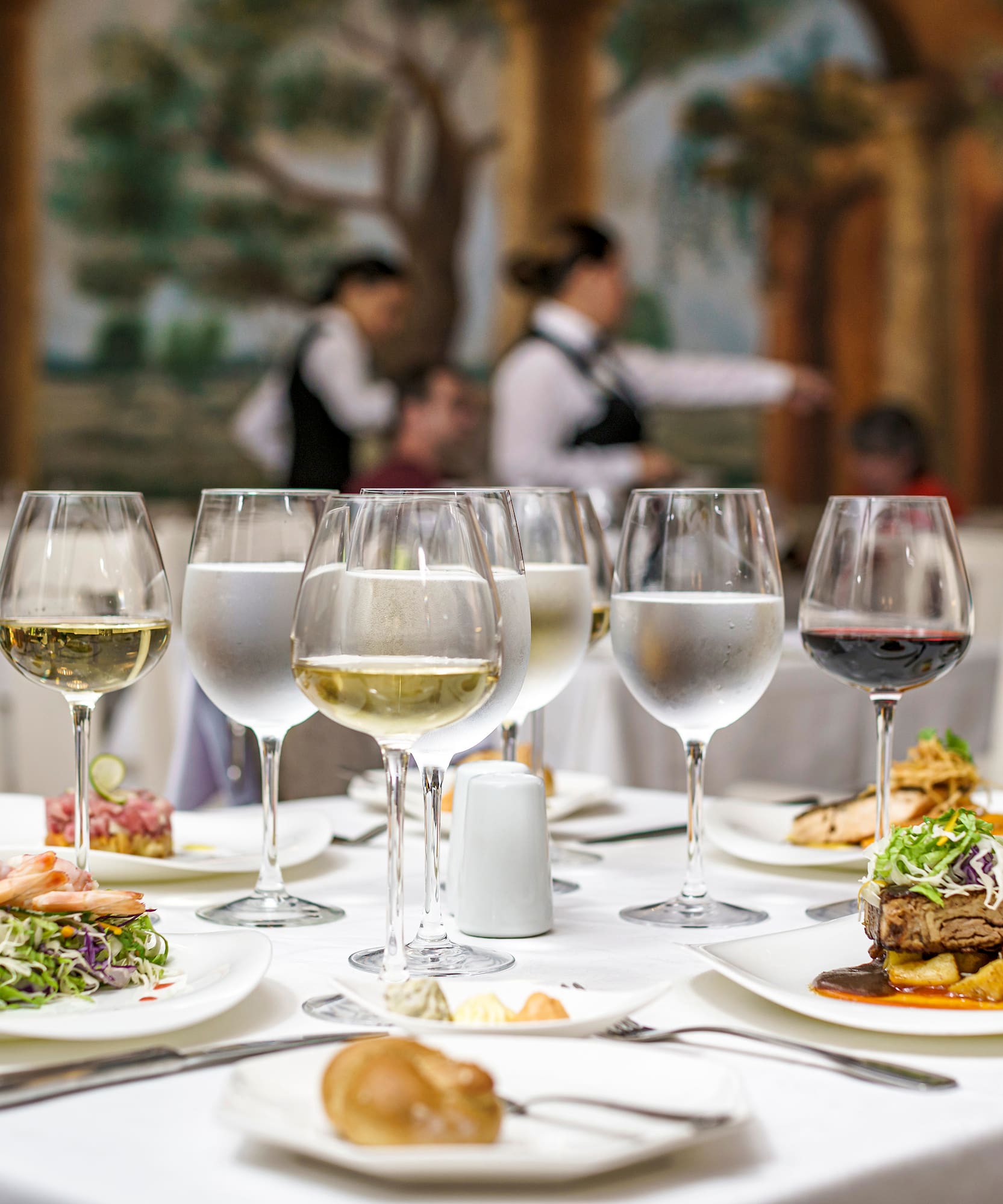 a table with plates of food and glasses of wine