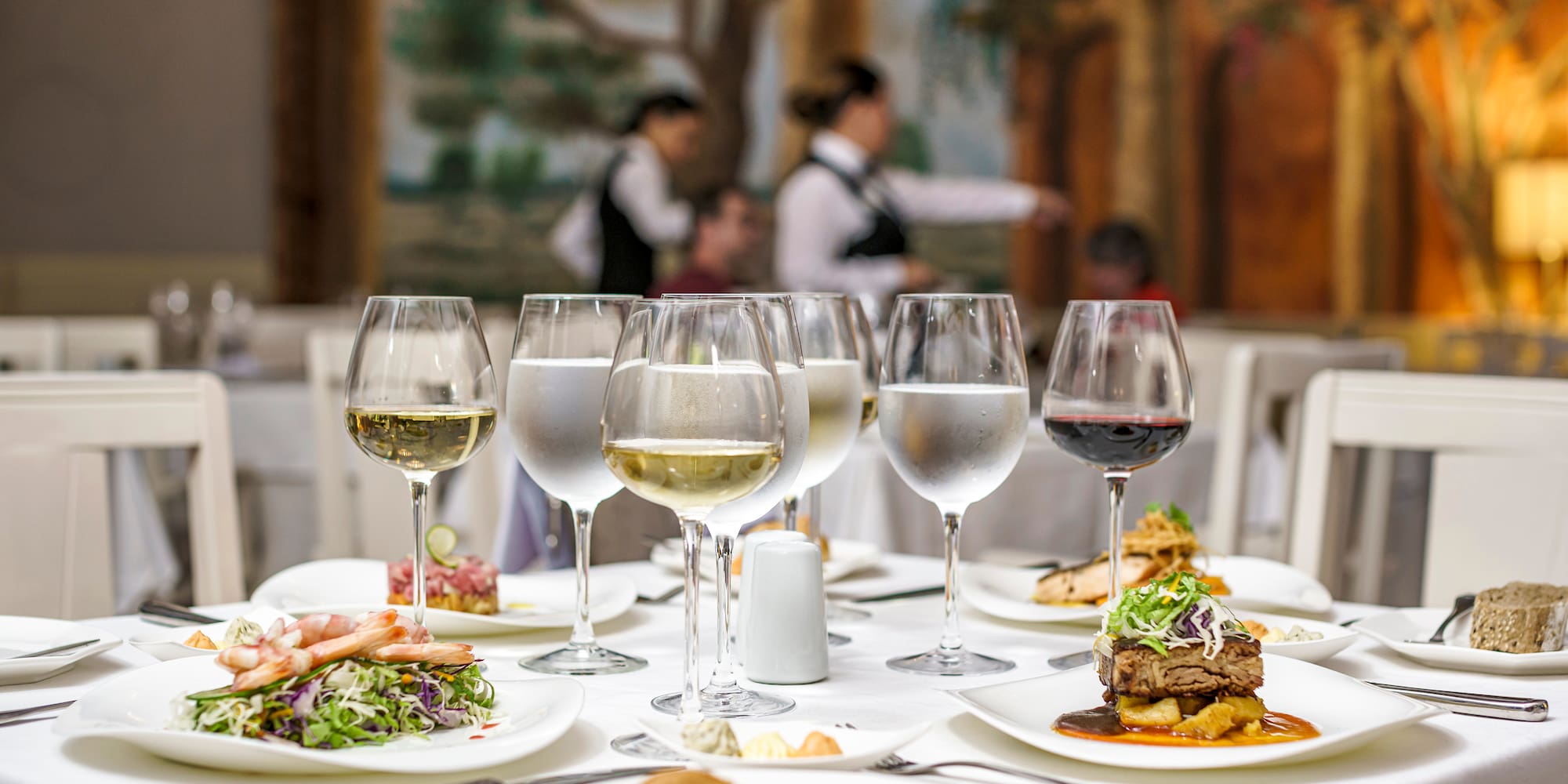 a table with plates of food and glasses of wine