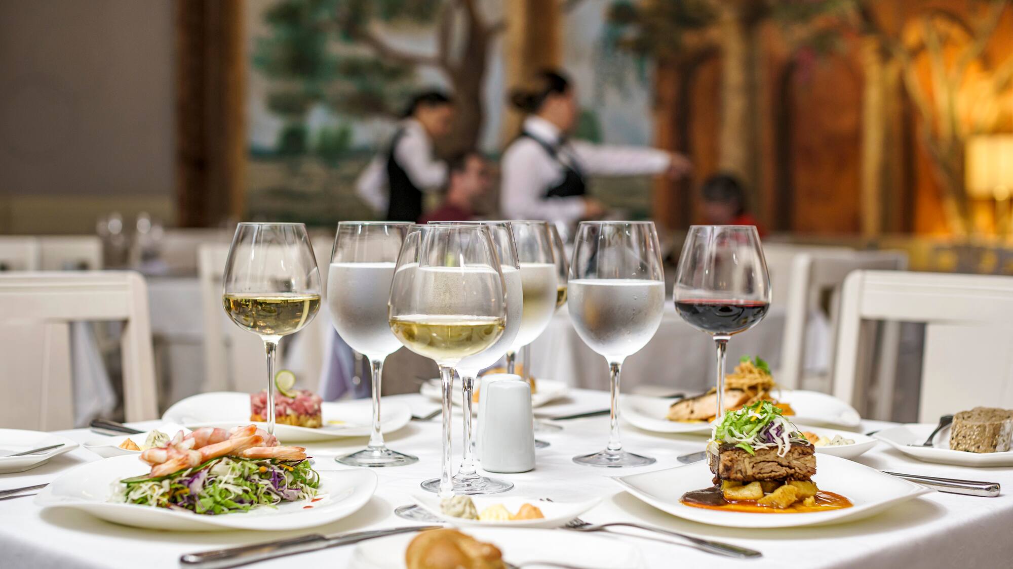 a table with plates of food and glasses of wine