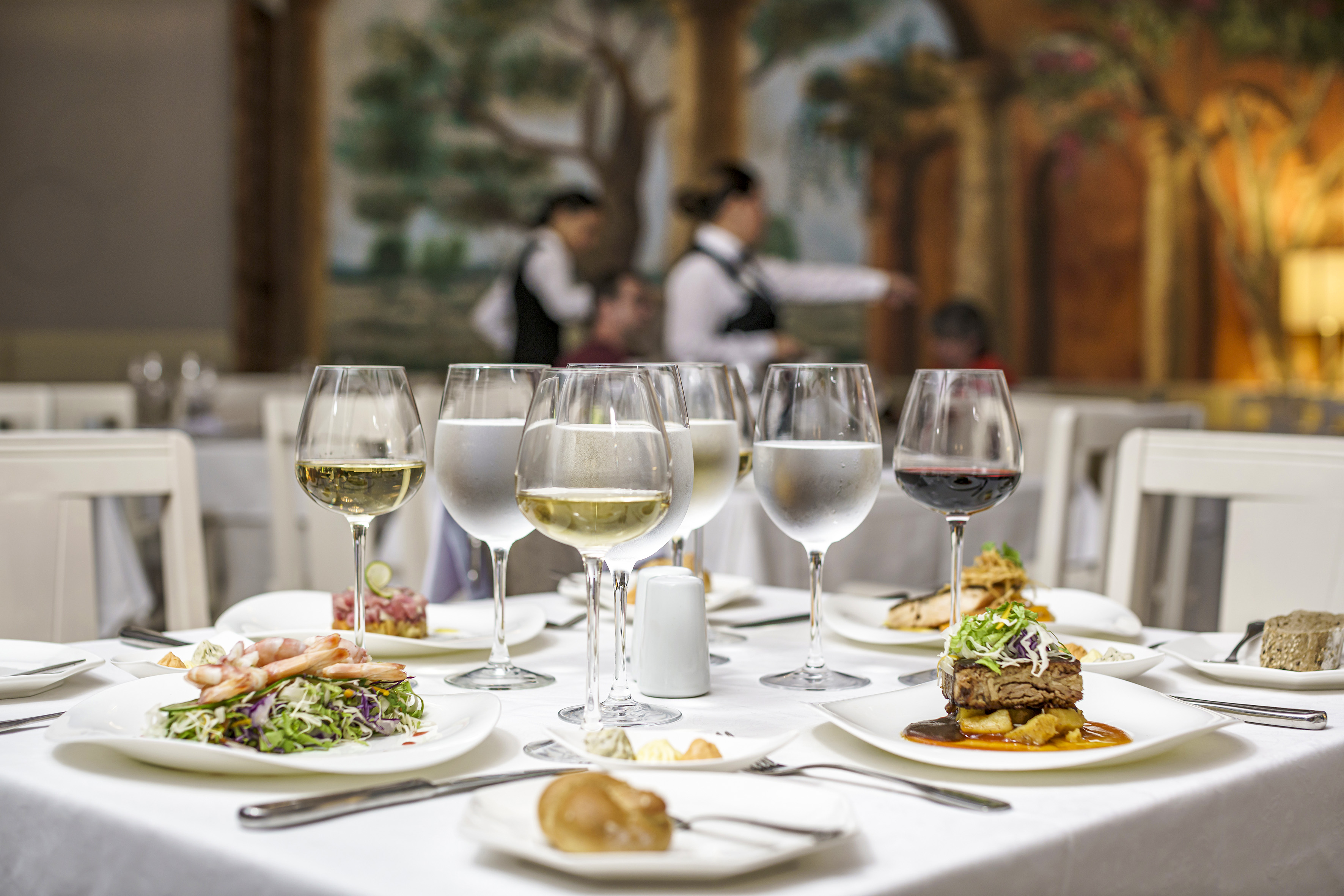 a table with plates of food and glasses of wine