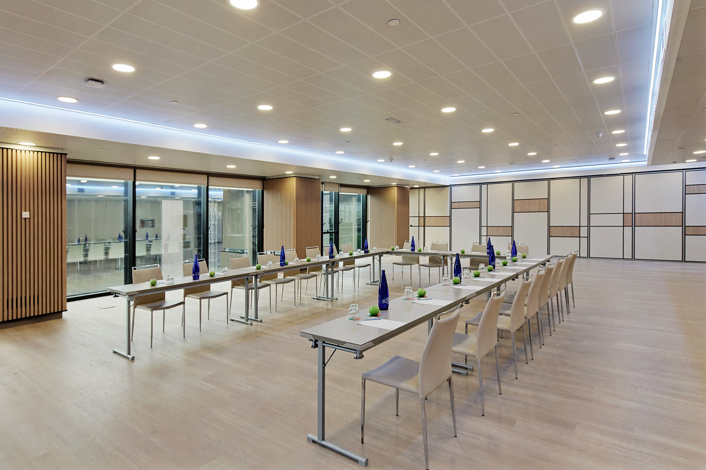 Modern meeting and event room with tables, chairs, water bottles, and modular walls.