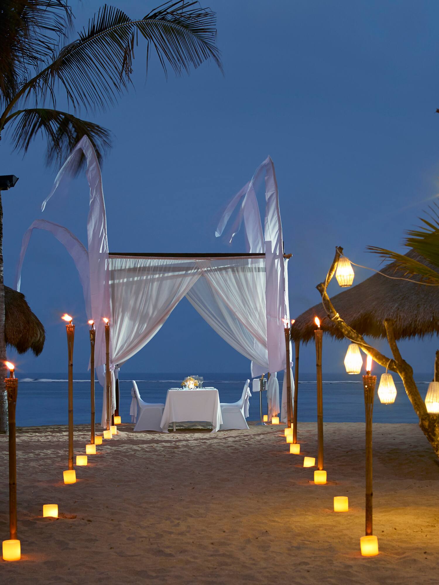 a beach with palm trees and a white tent