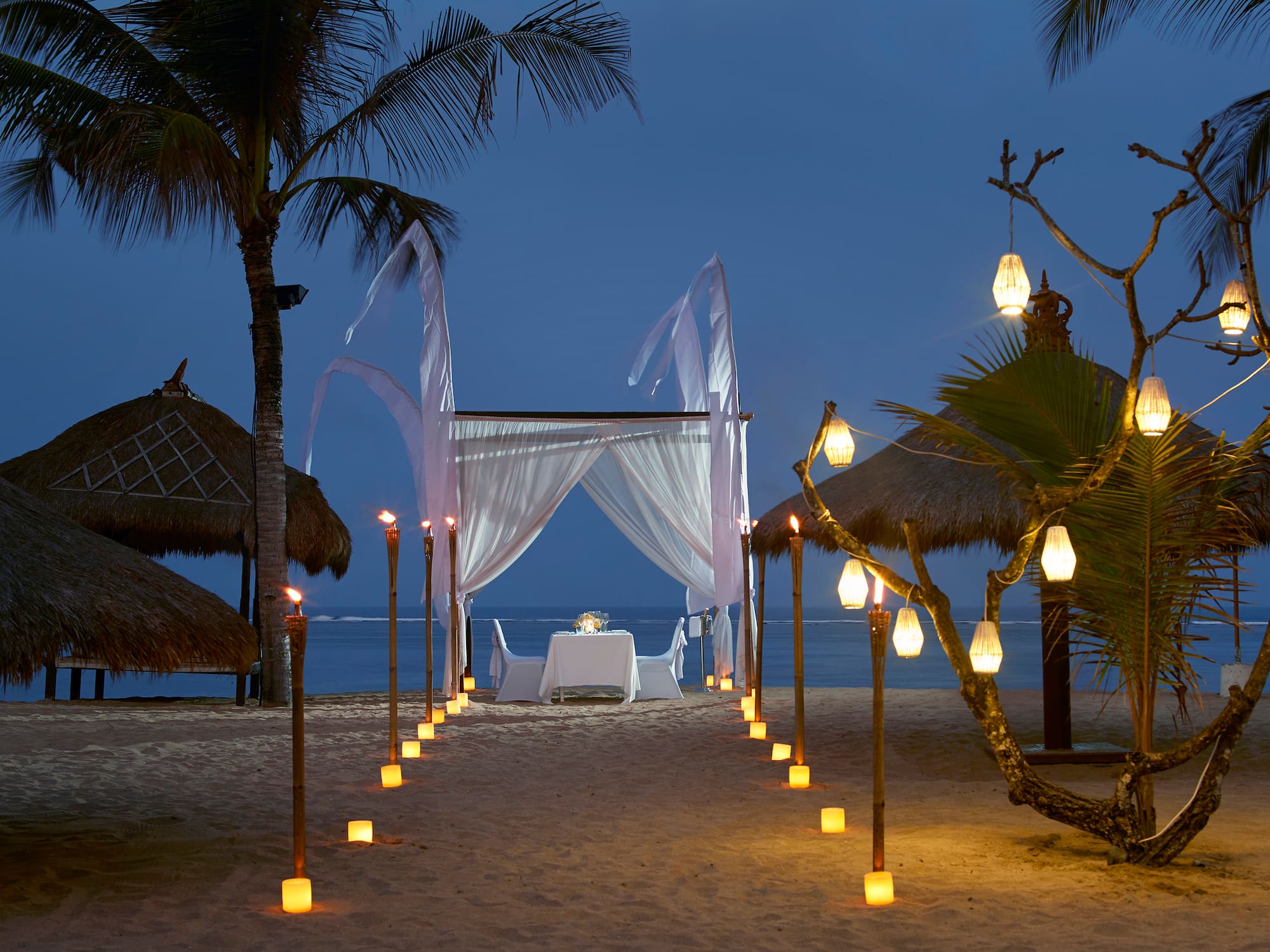 a beach with palm trees and a white tent