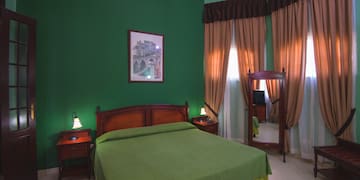 a green bedroom with a mirror and a bed