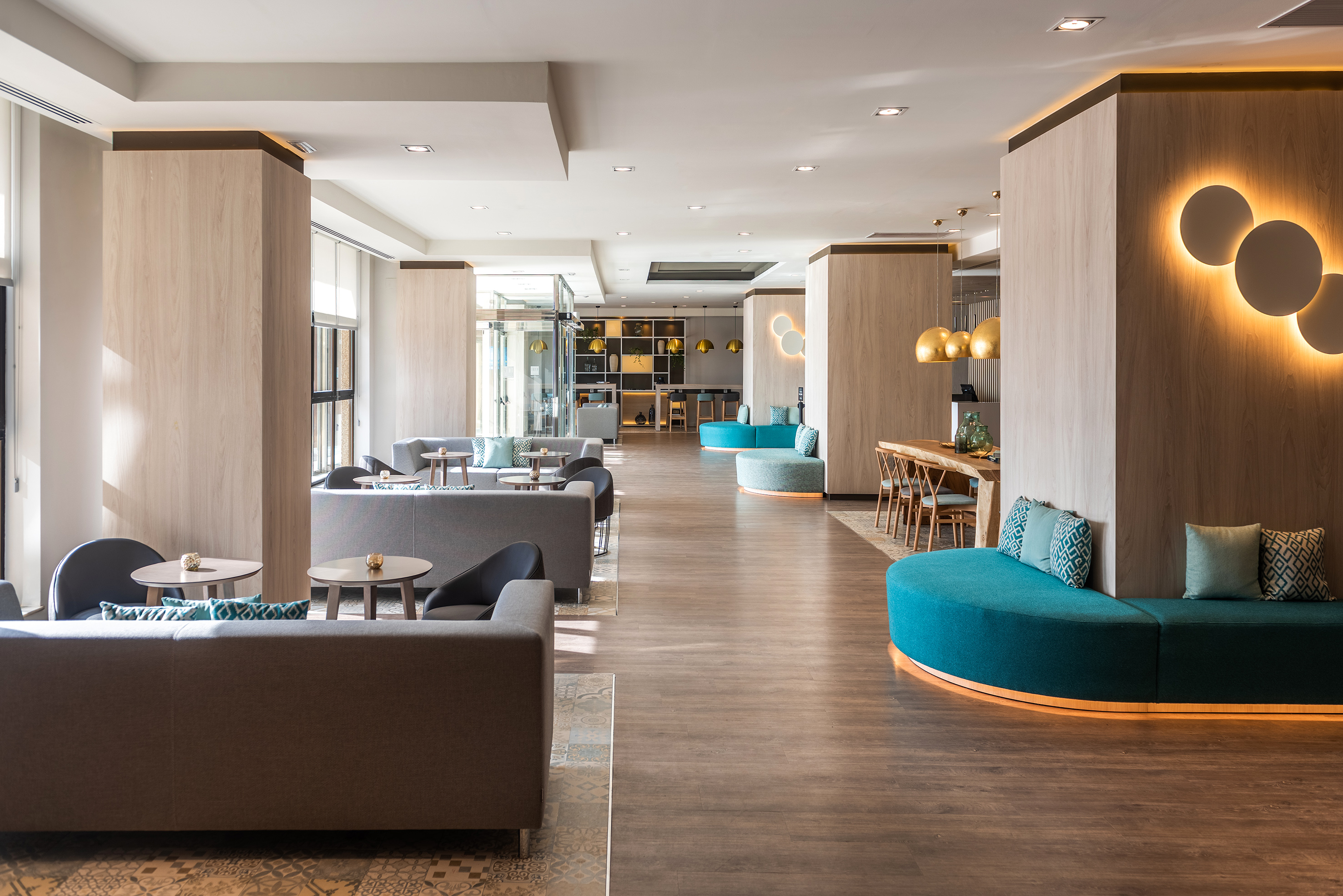 Modern hotel lobby with wood accents, teal seating, and contemporary lighting.