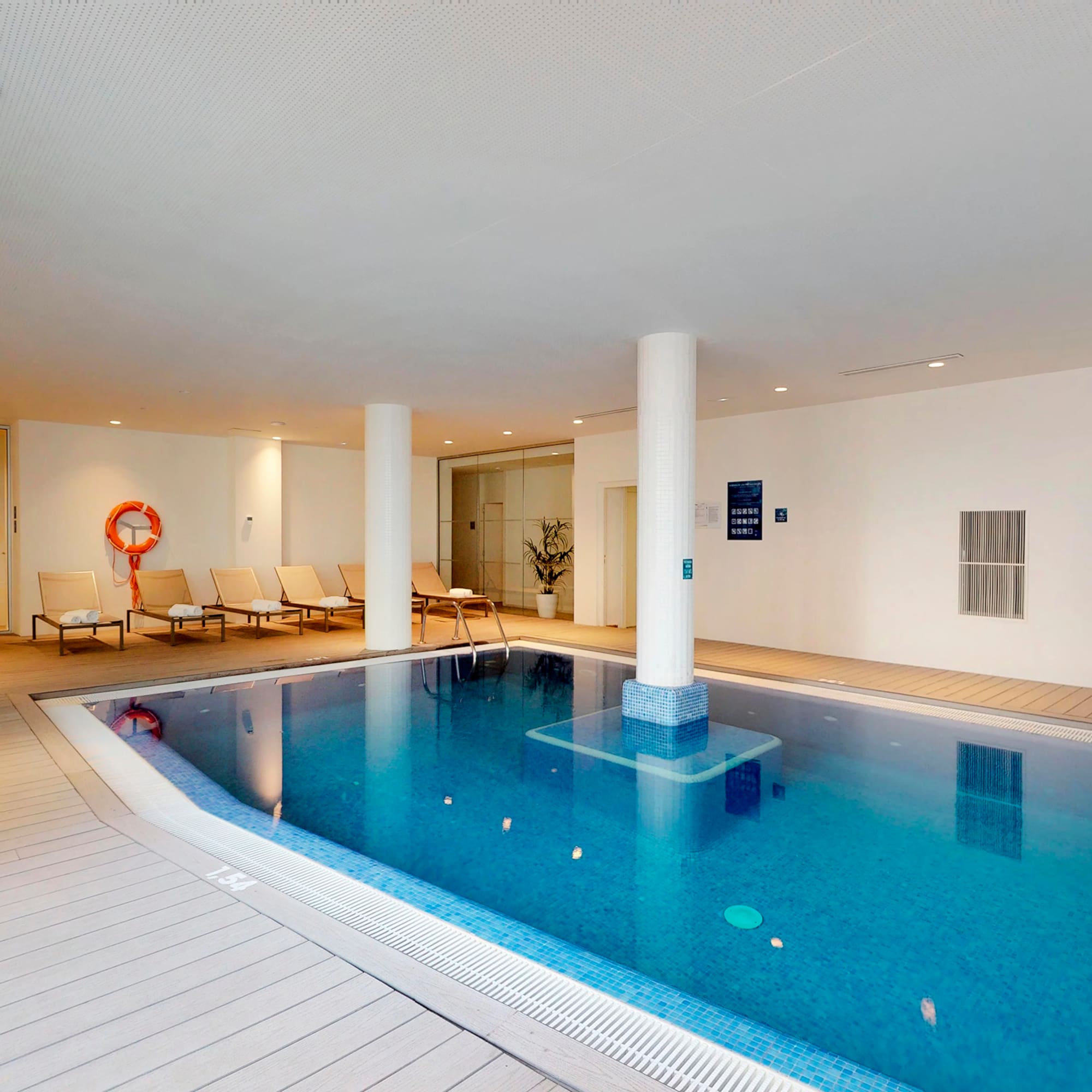 a swimming pool with a white pole and chairs