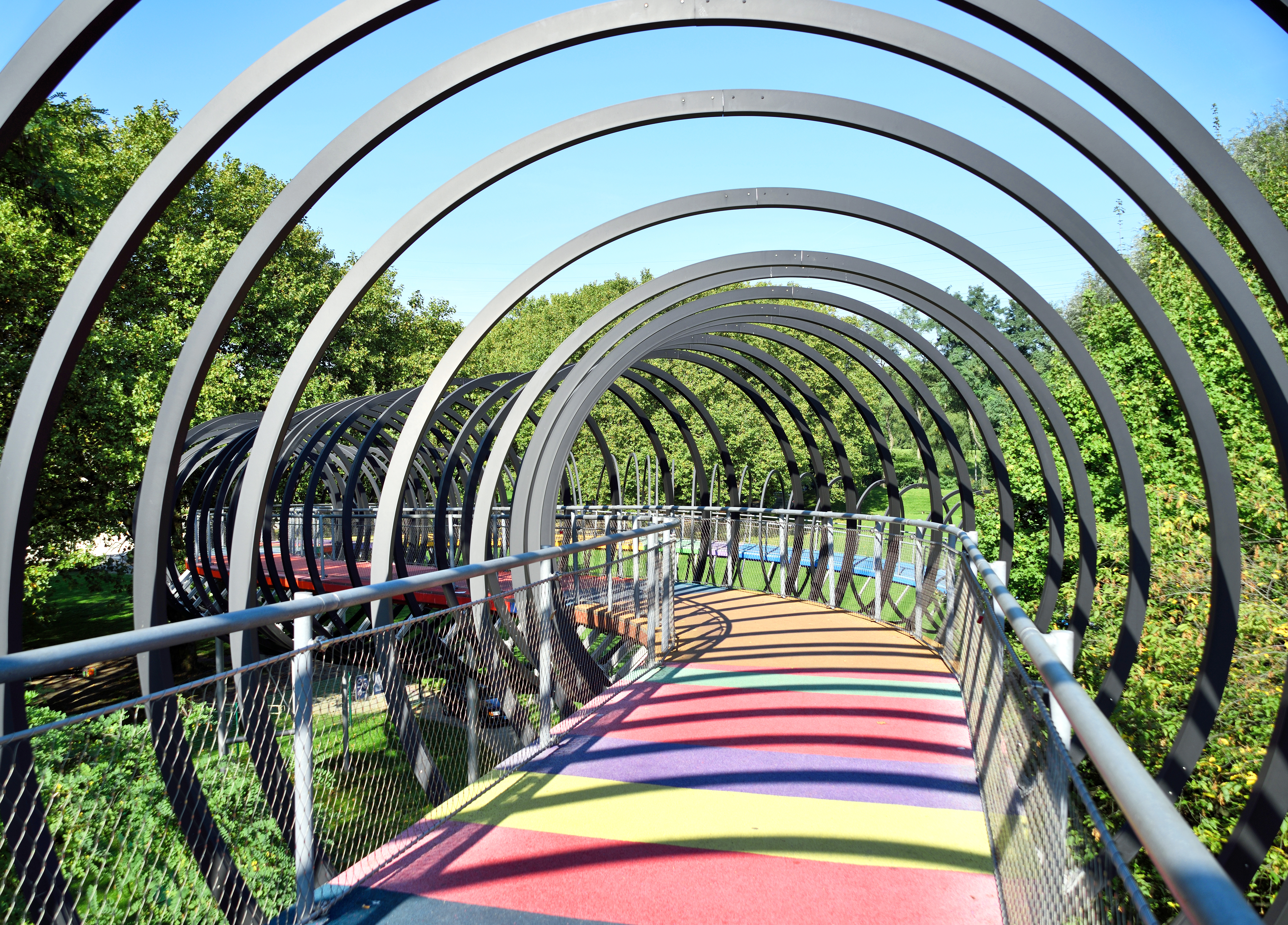 a colorful walkway with metal railings and trees