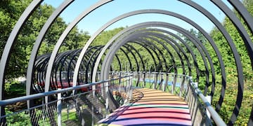 a colorful walkway with metal railings and trees