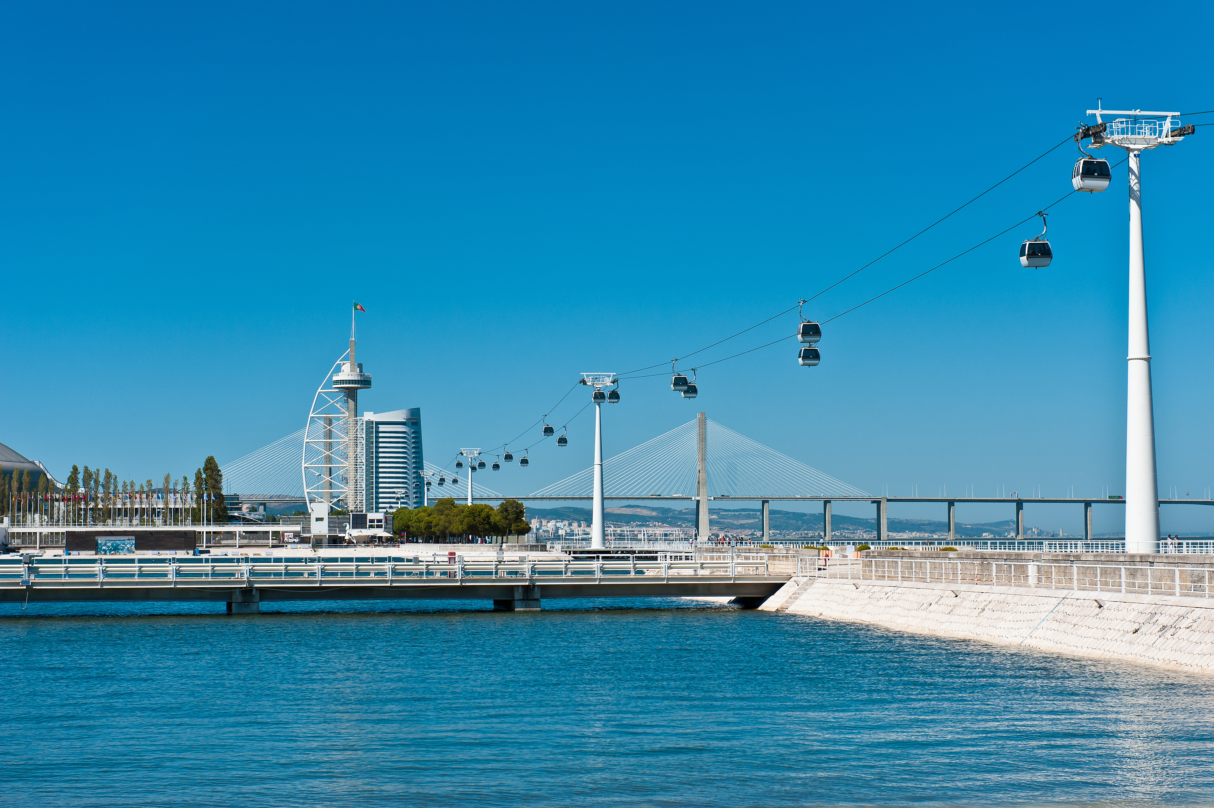 Lisbon Parque das Nações: cable cars, Vasco da Gama Tower, and bridge over blue water.