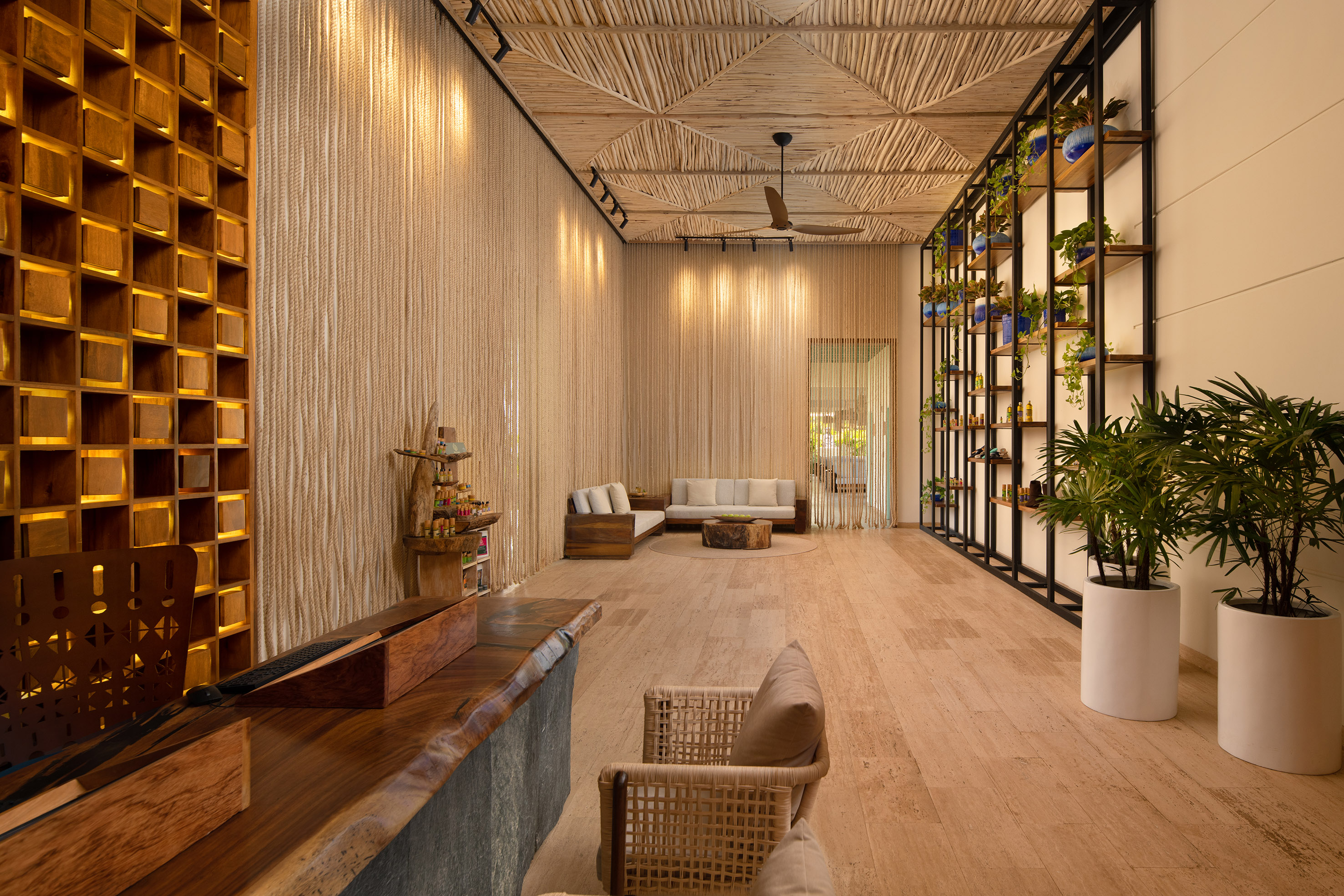Inviting resort lobby with natural wood desk, rope walls, and plant decor.