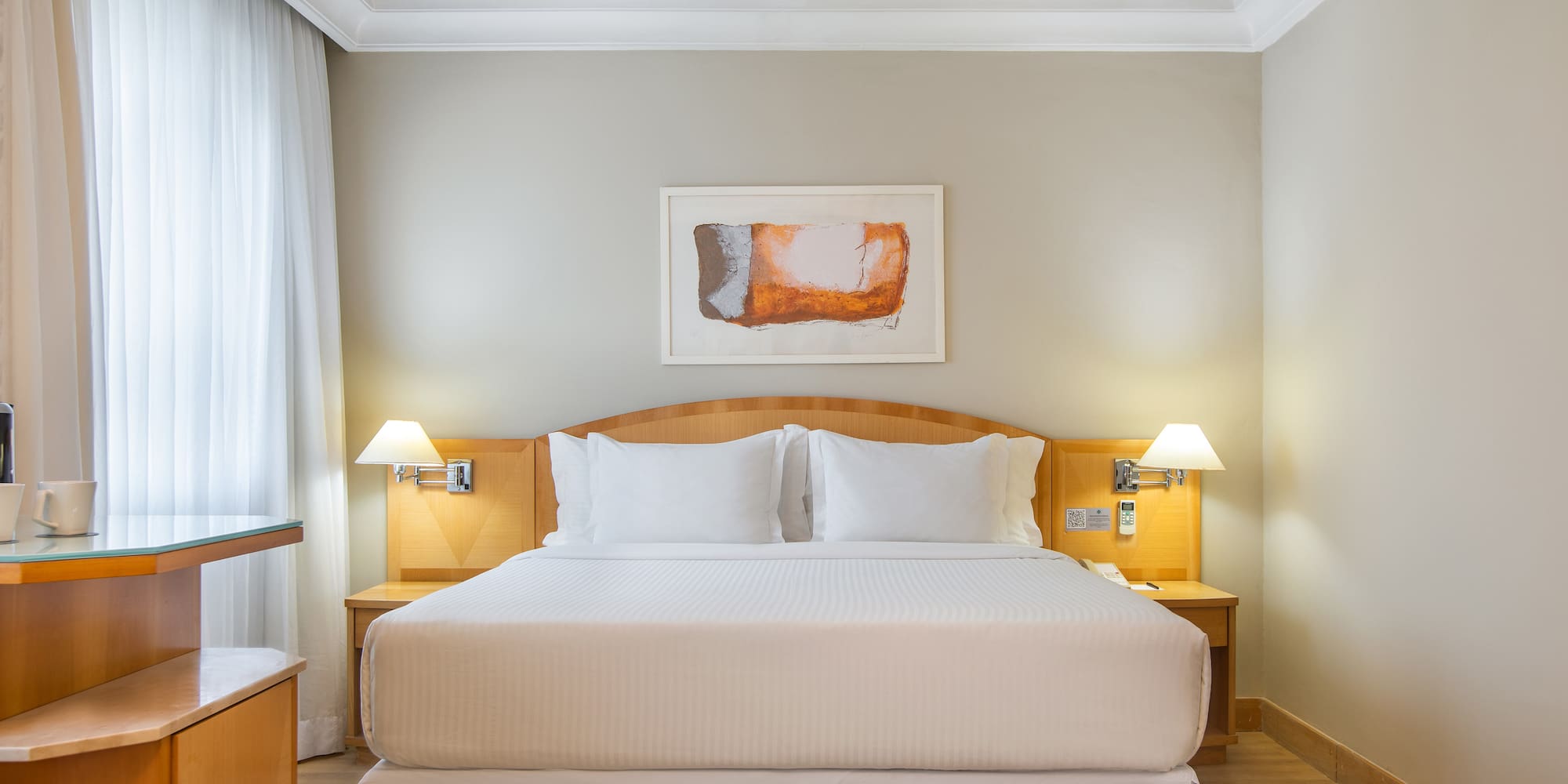 a bed with white sheets and lamps in a room