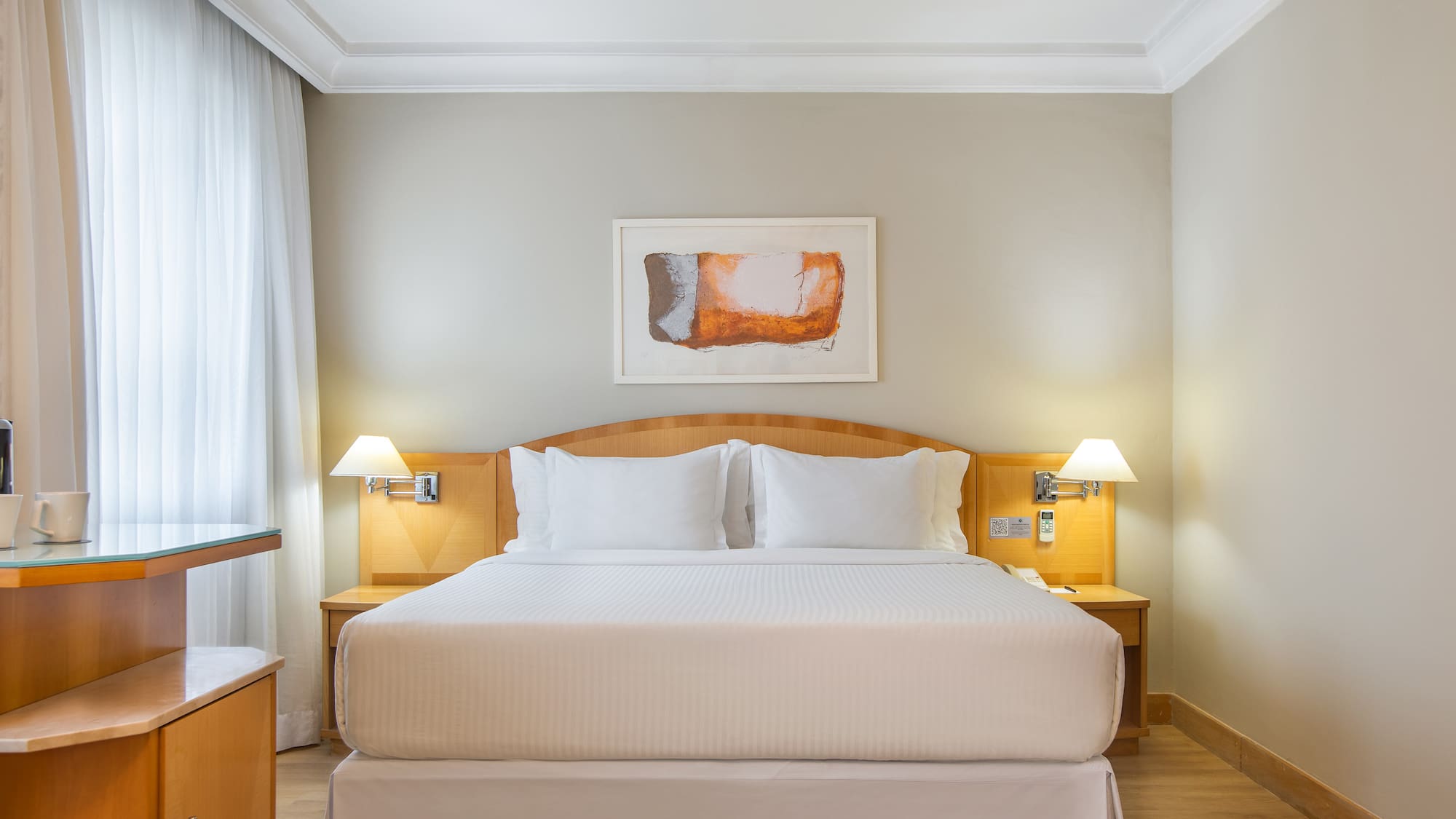 a bed with white sheets and lamps in a room