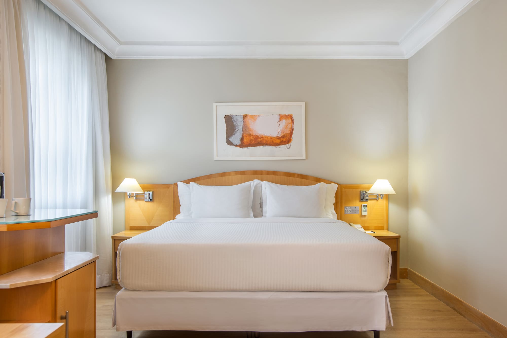 a bed with white sheets and lamps in a room