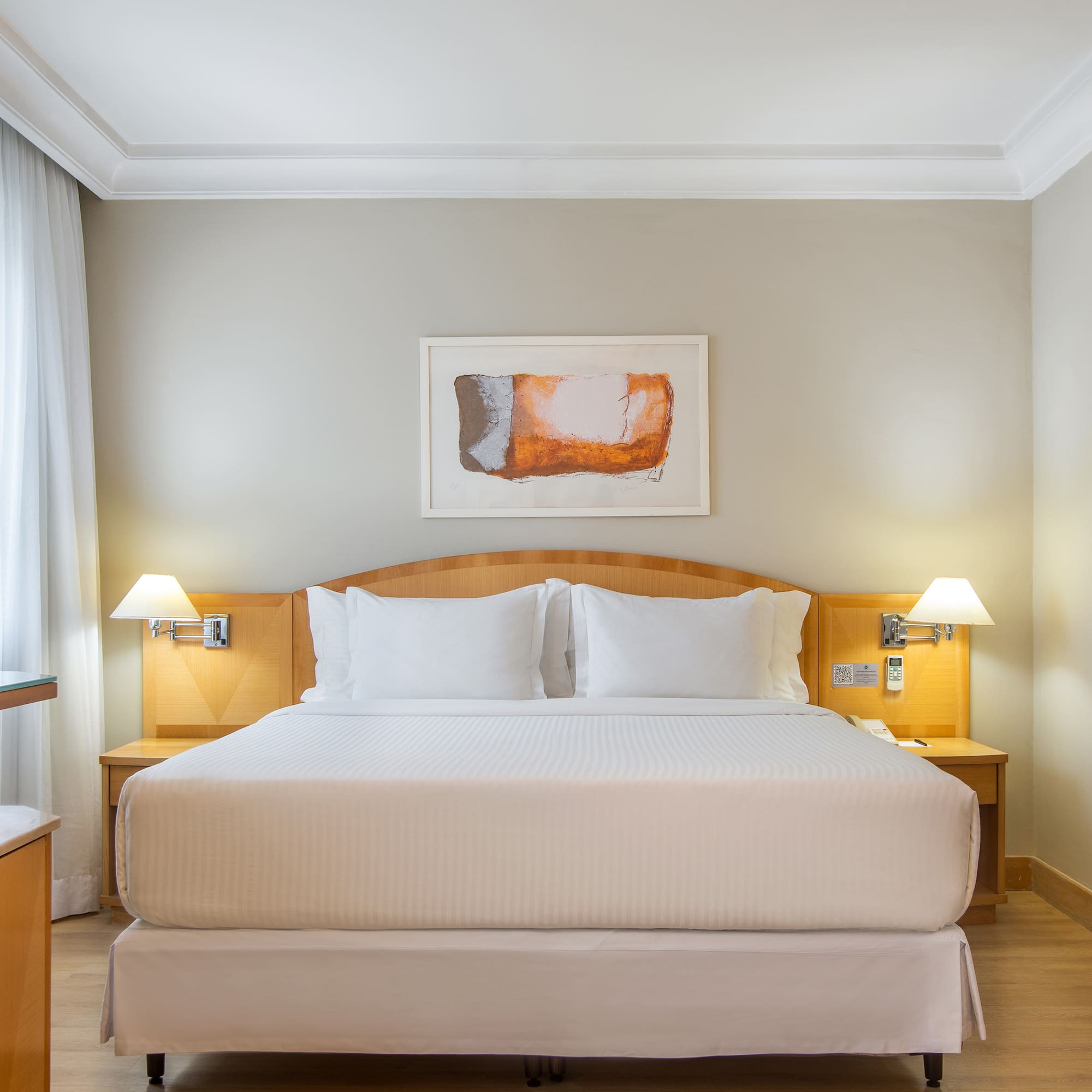 a bed with white sheets and lamps in a room