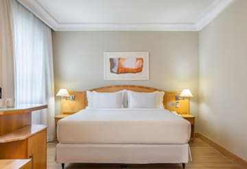 a bed with white sheets and lamps in a room