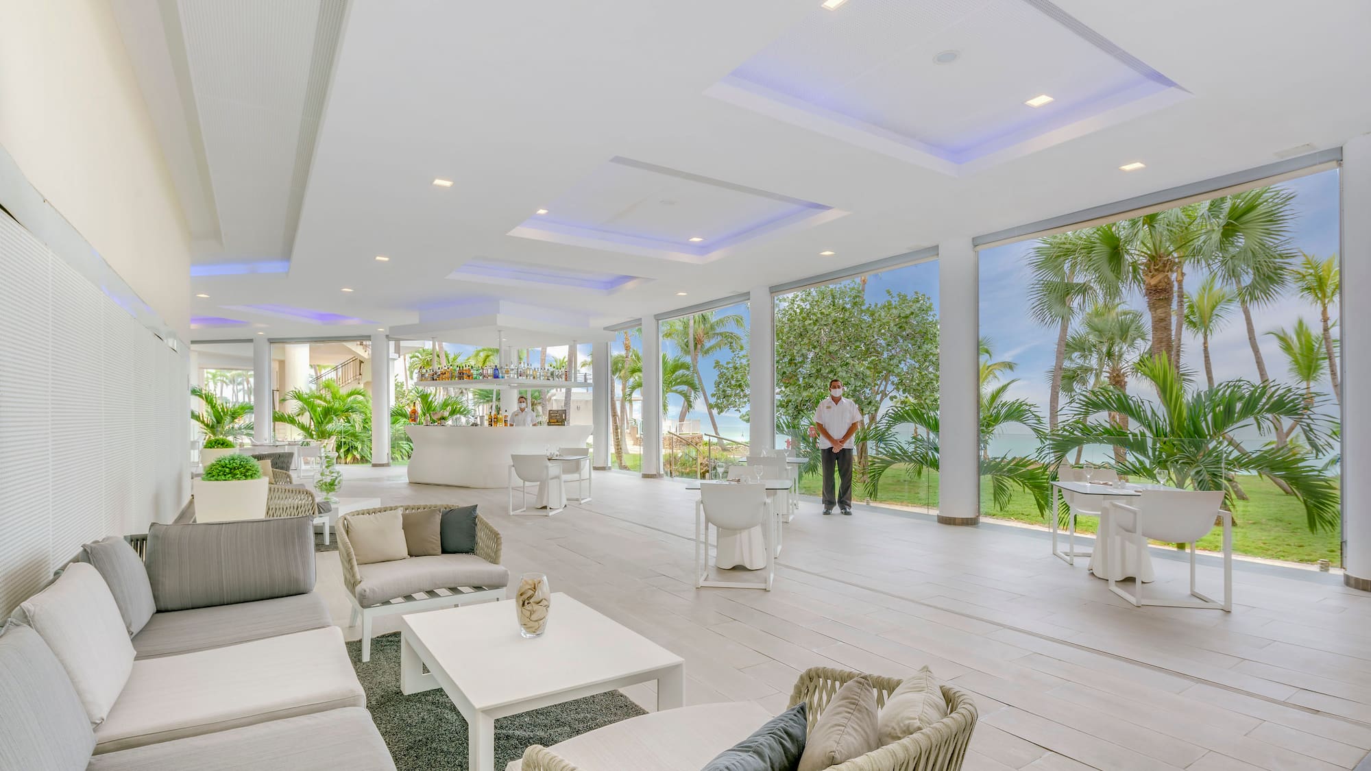 a man standing in a room with white furniture and tables