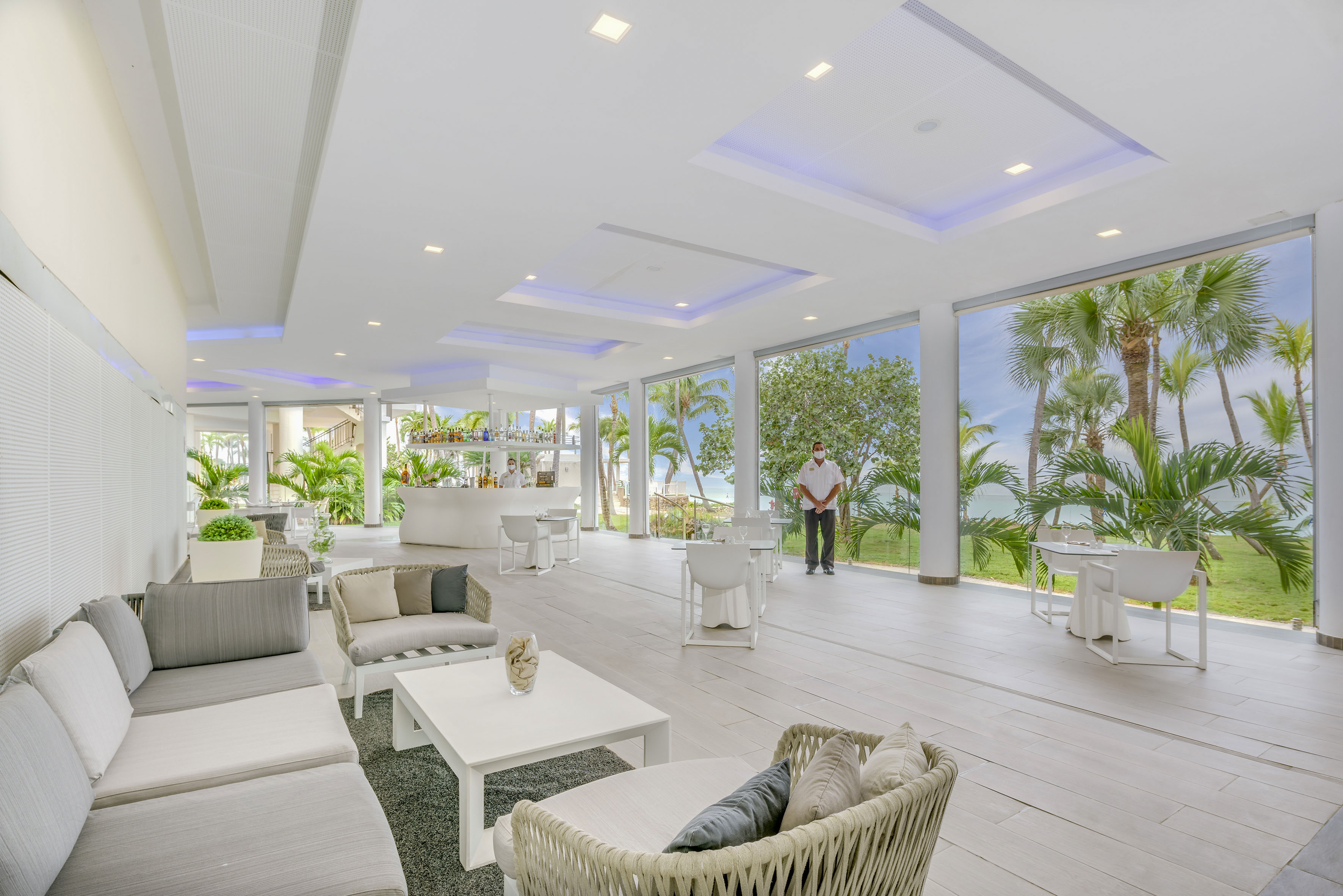 a man standing in a room with white furniture and tables