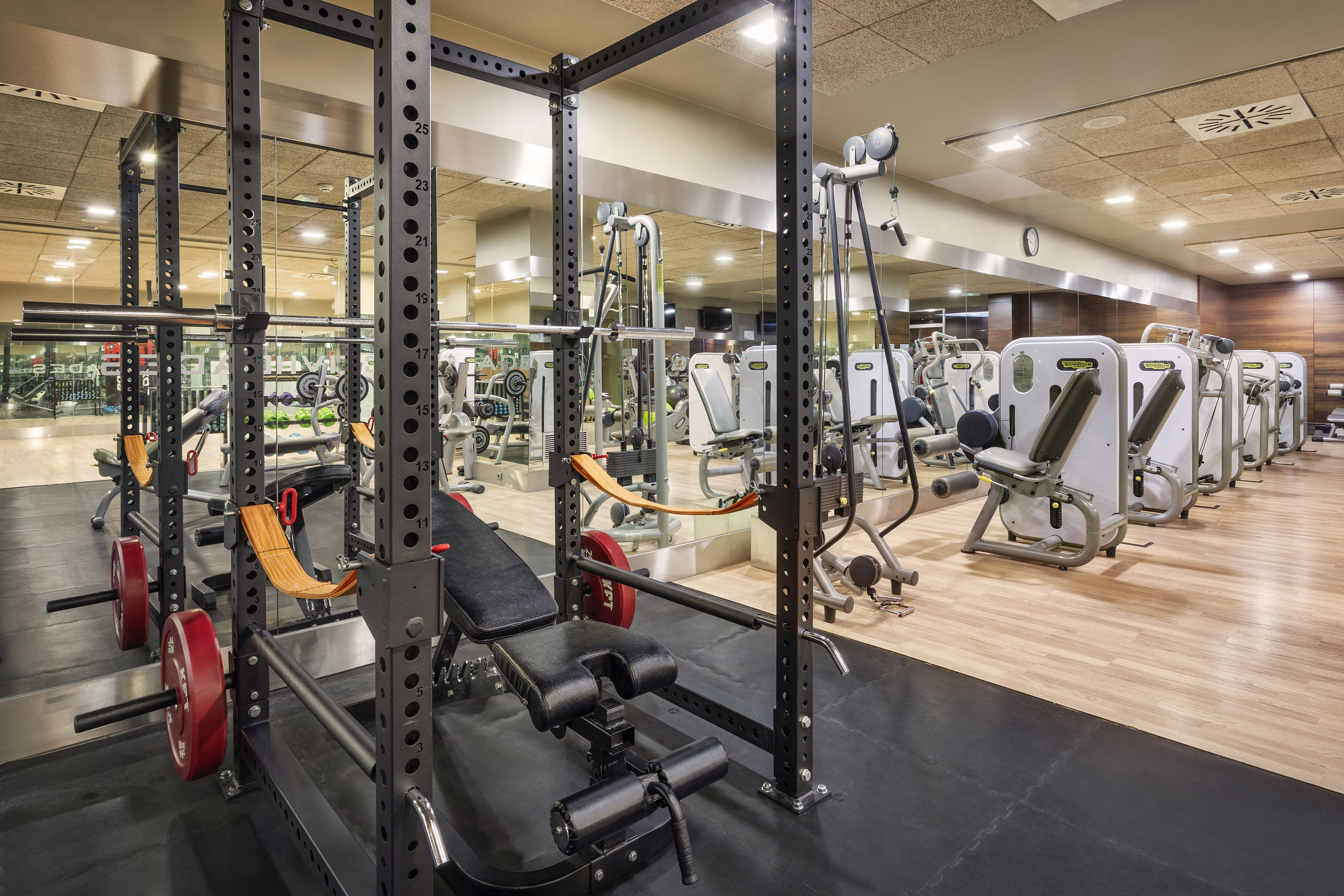 Modern gym with power racks, barbells, weight benches, and fitness machines.