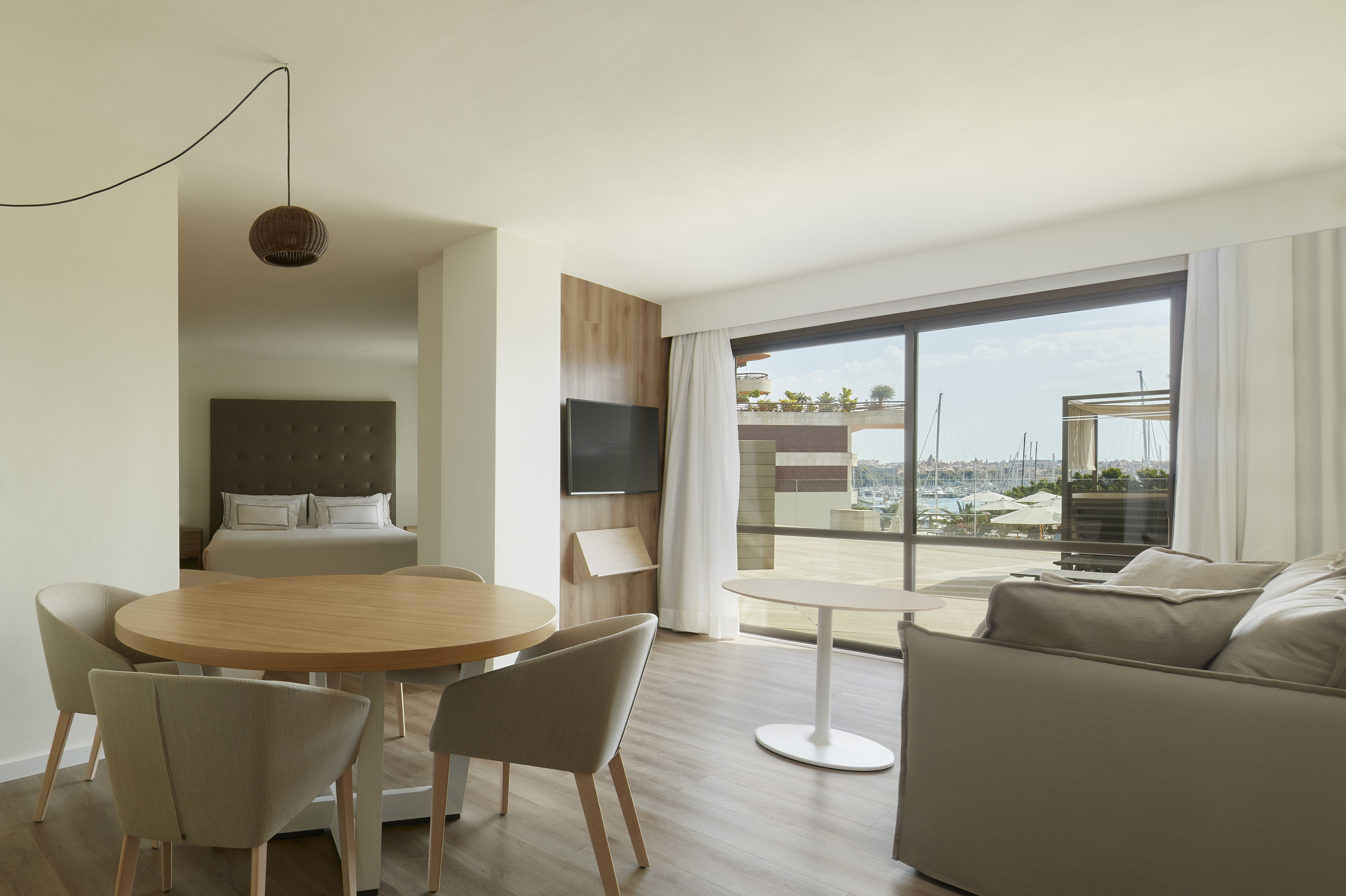 Modern hotel suite with living room, dining area, bedroom, and marina view.