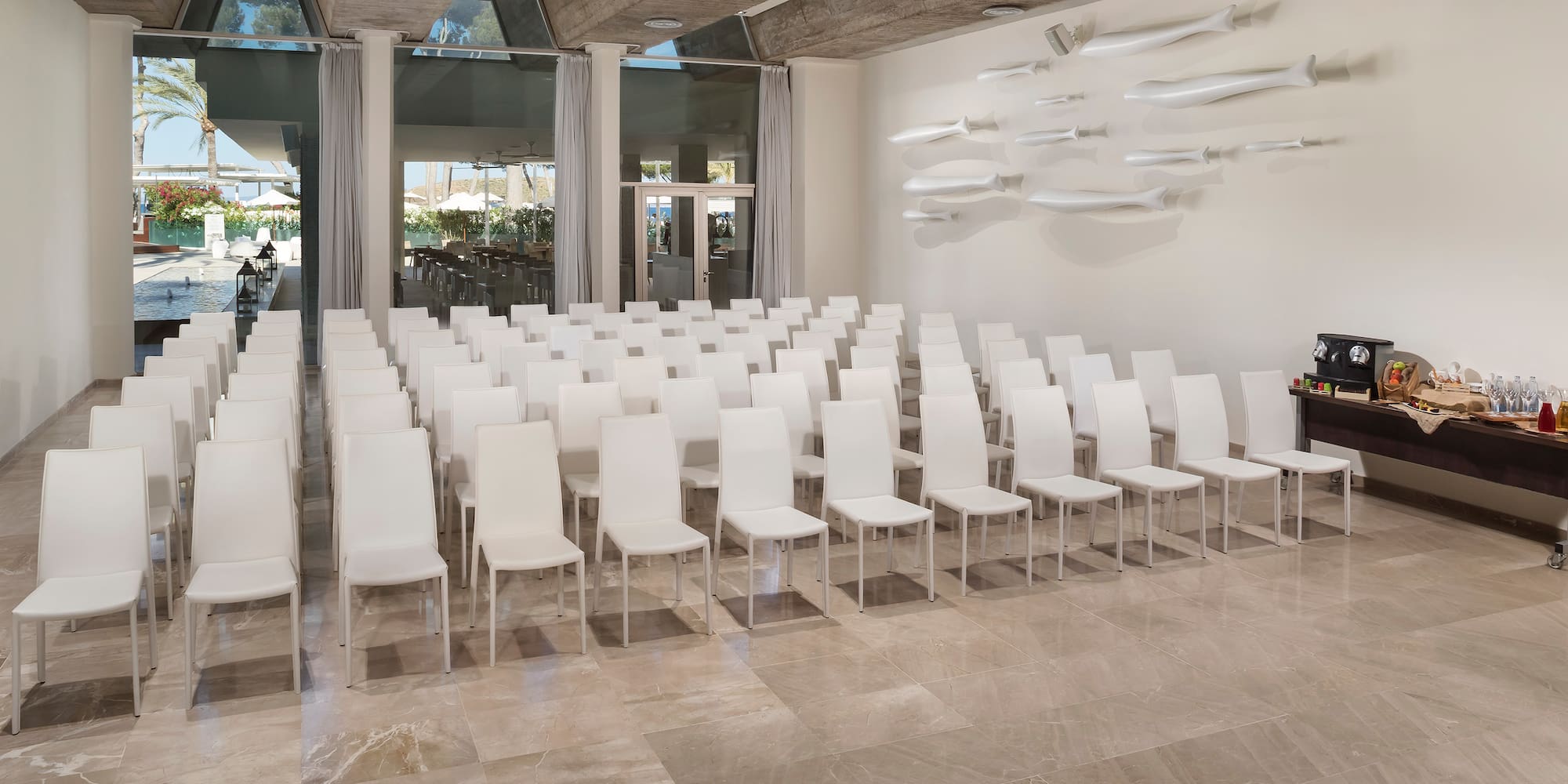 a room with white chairs and a man standing in front of a wall