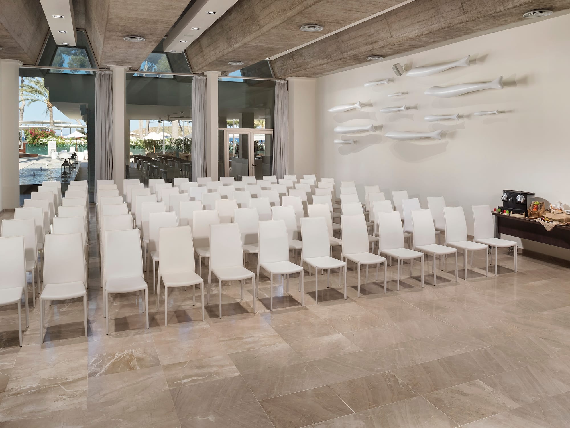 a room with white chairs and a man standing in front of a wall