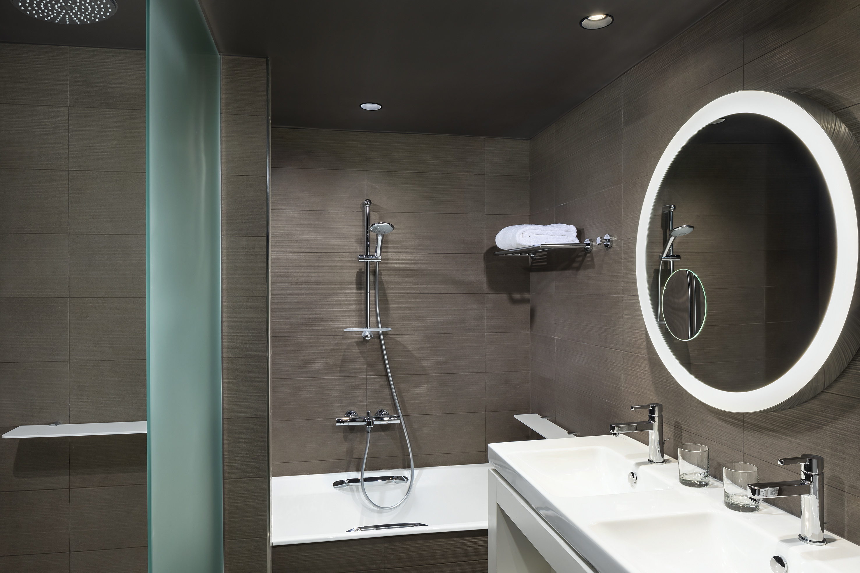 Modern bathroom with double vanity, bathtub, shower, and LED mirror.