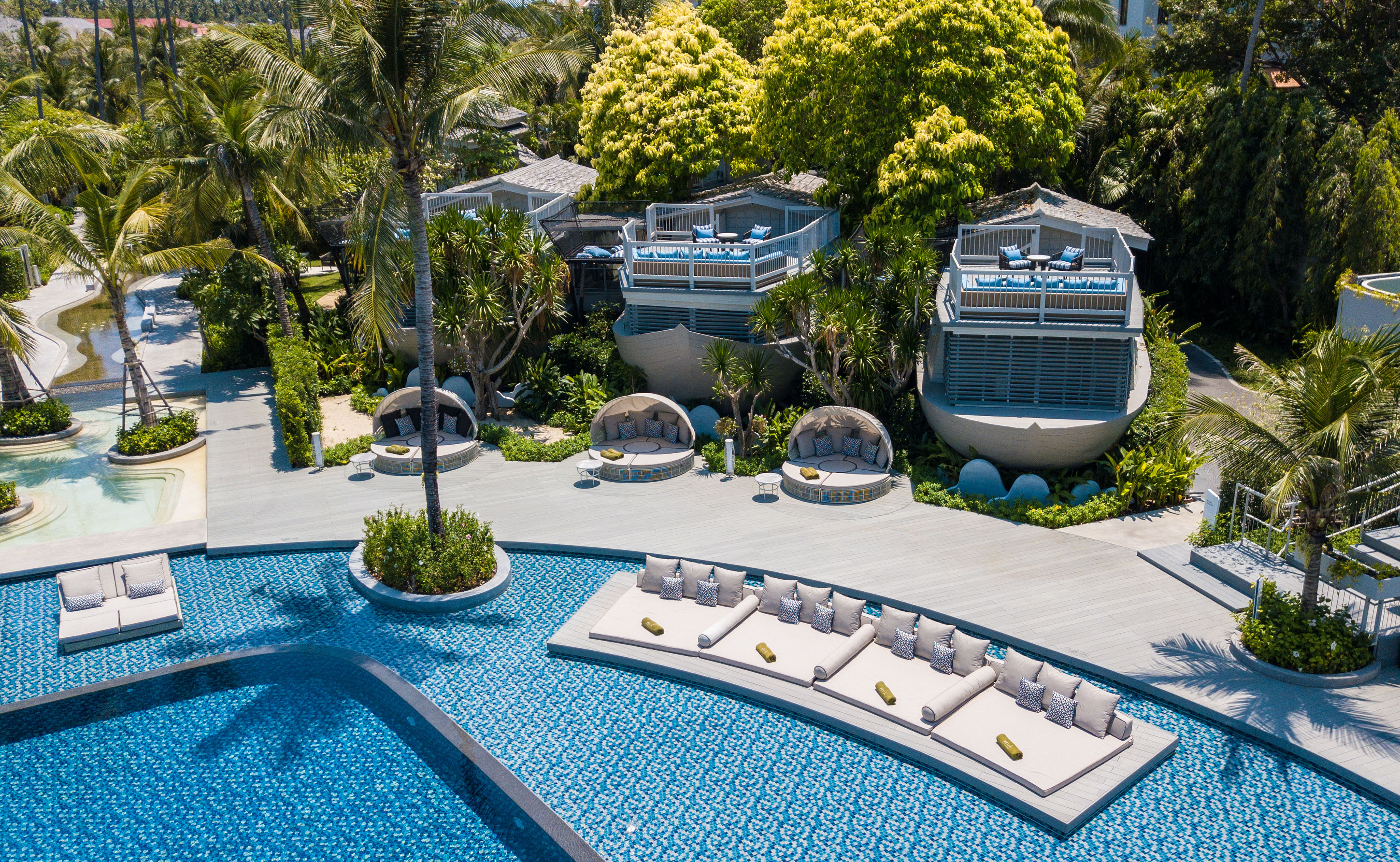 Aerial view of luxury tropical resort pool, floating loungers, and unique villas.