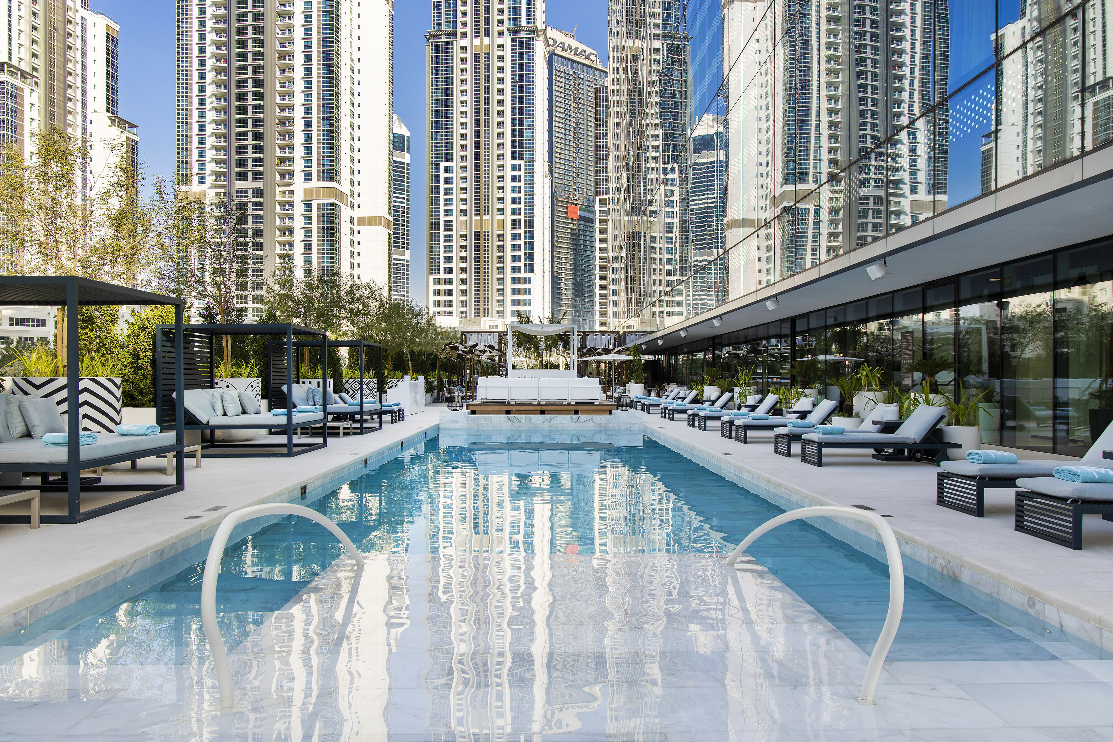 Luxury urban pool with skyscrapers reflecting in water and building glass.