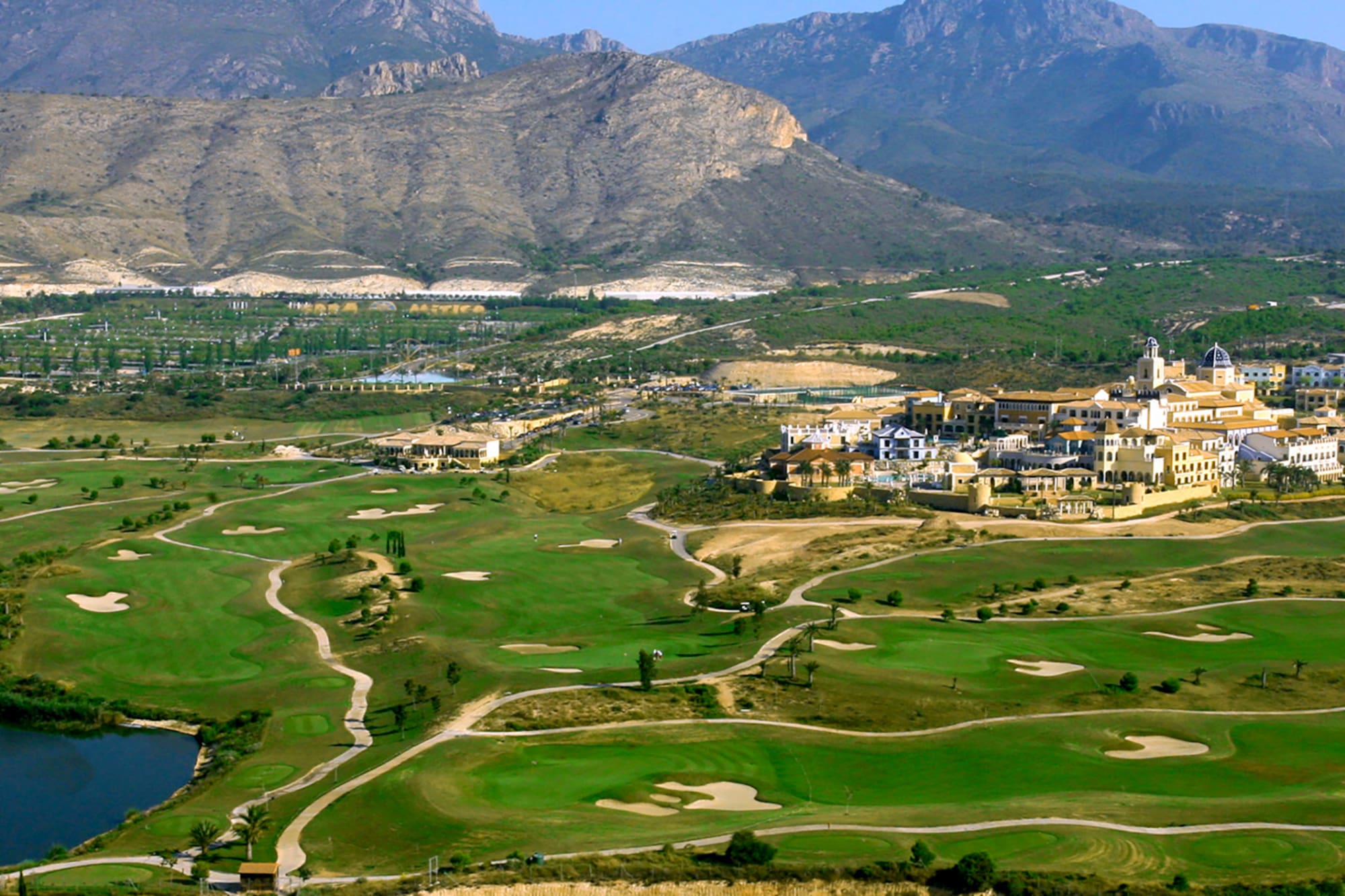 Golf resort with Mediterranean village, lake, and mountains in Benidorm.