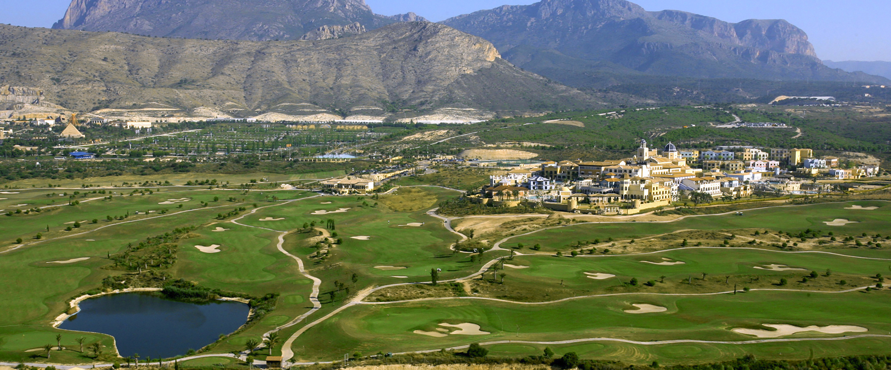 Golf resort with Mediterranean village, lake, and mountains in Benidorm.