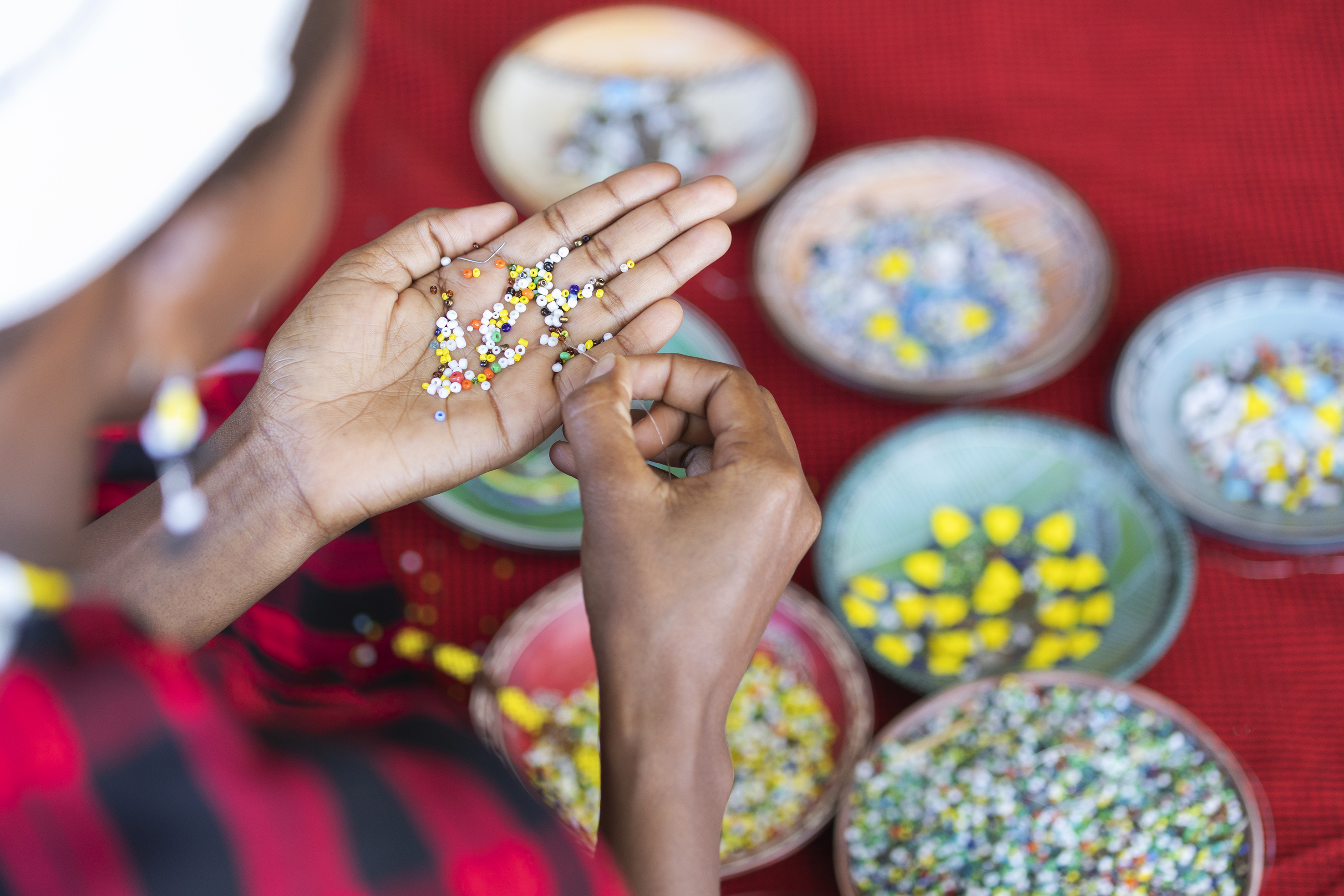 Artisan hands beading colorful small beads for jewelry craft.
