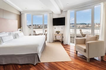 a room with a bed and chairs and a balcony