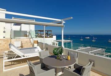 a patio with a table and chairs overlooking the ocean
