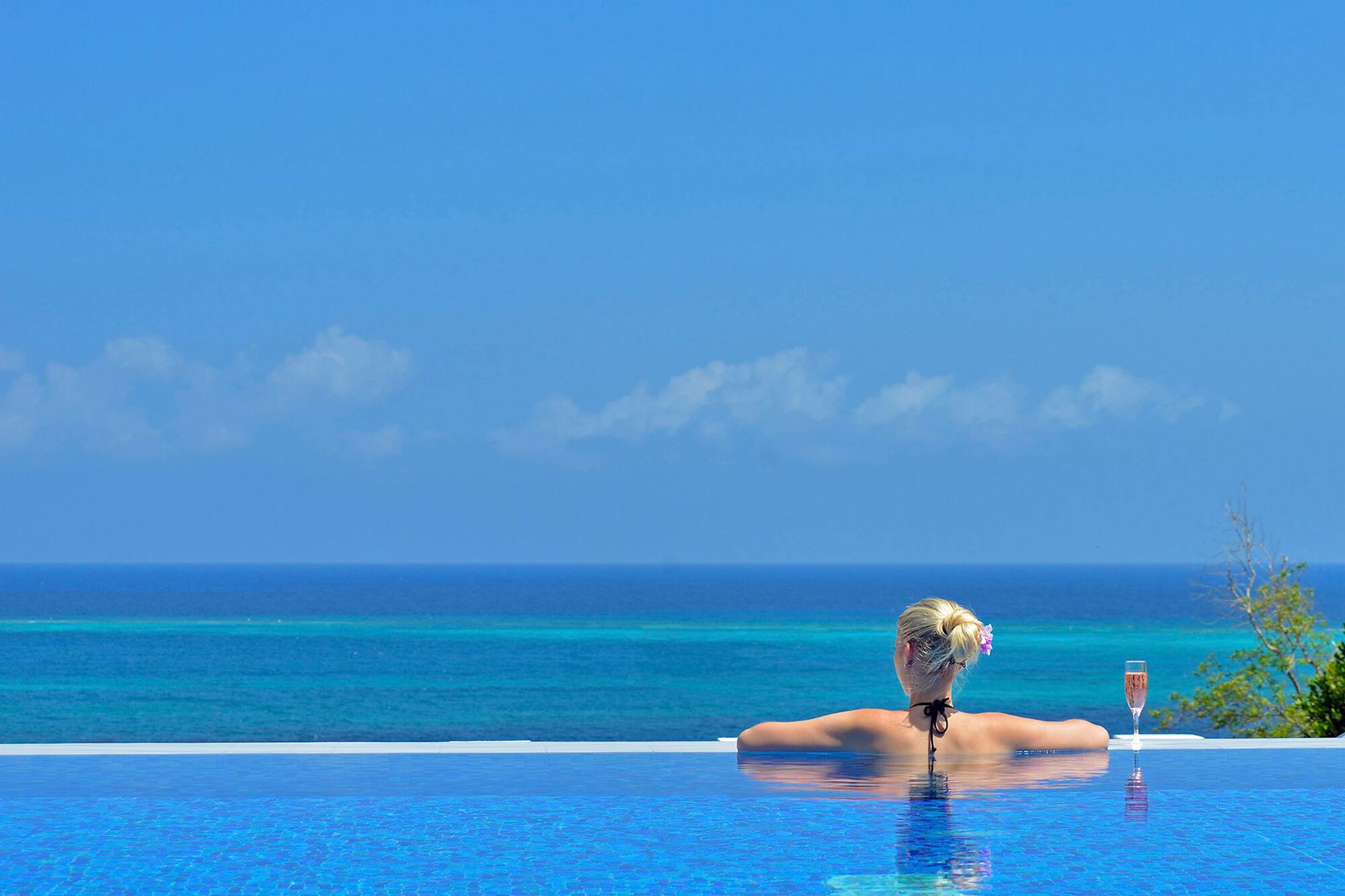 a woman in a pool with a body of water in the background