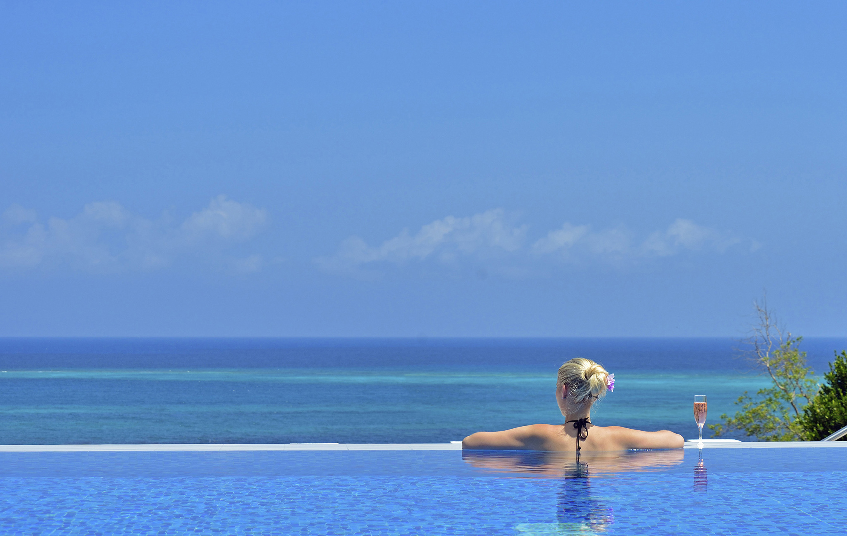 a woman in a pool with a body of water in the background