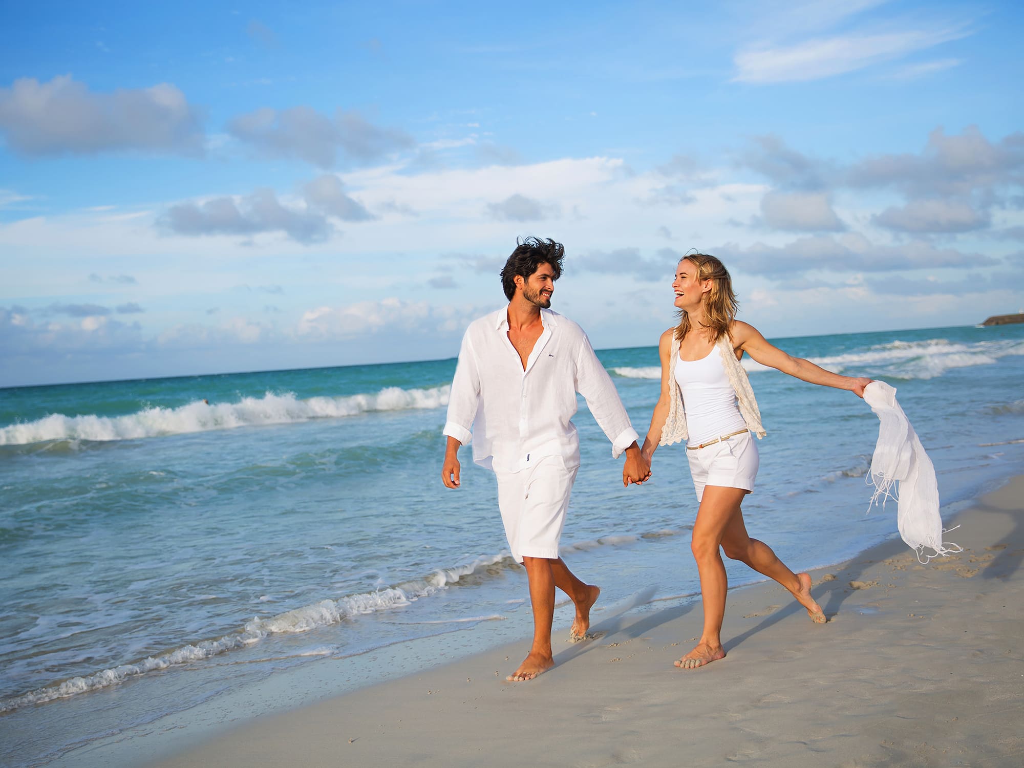 a man and woman holding hands on a beach