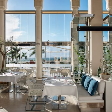 a room with white tables and chairs and a large window
