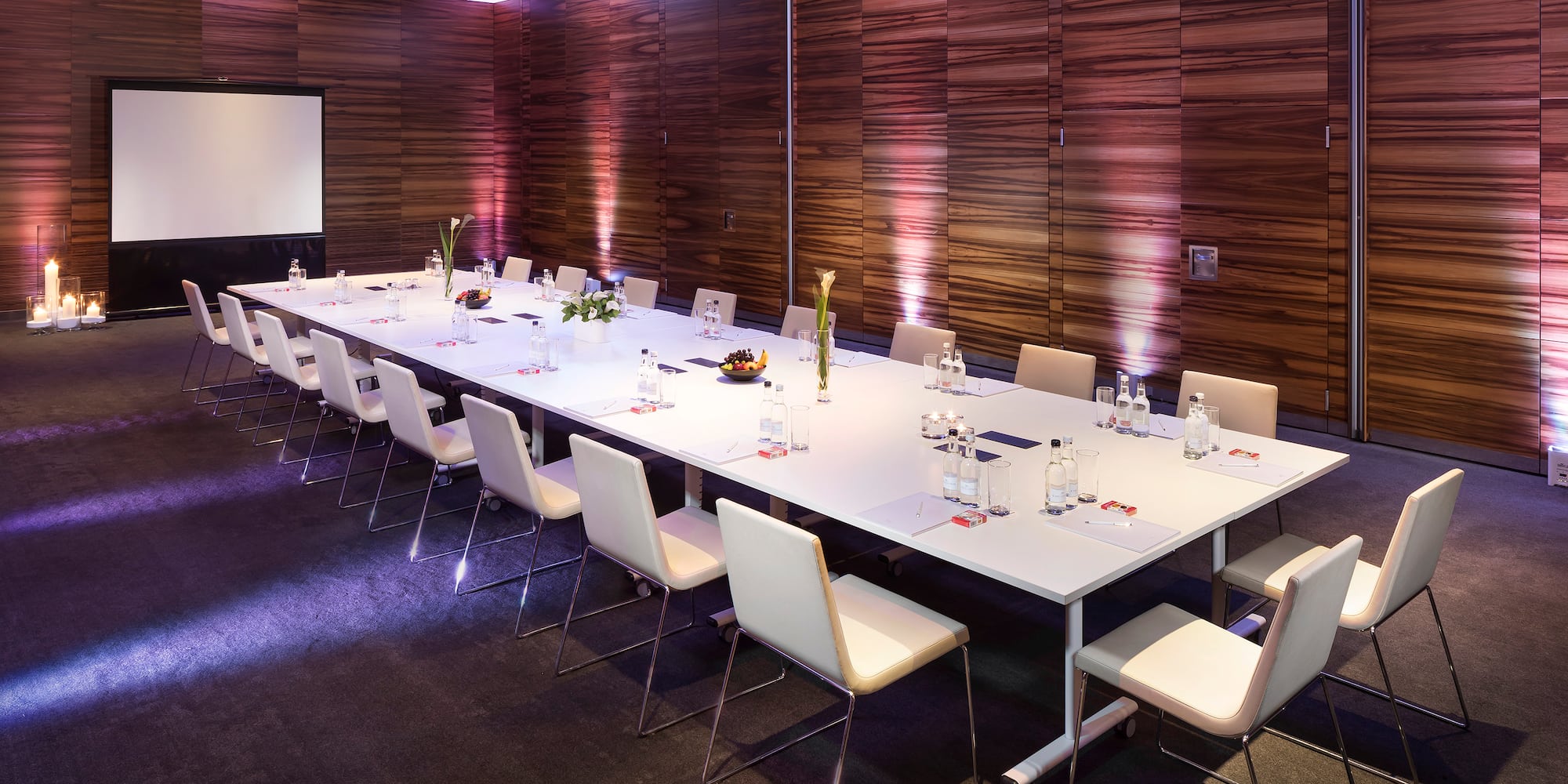 a long conference table with chairs and a projector screen
