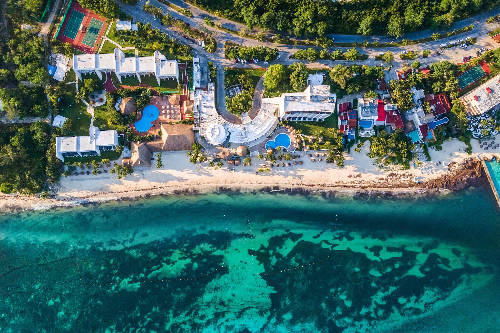 Resort de lujo junto a playa caribeña y mar turquesa, vista aérea.