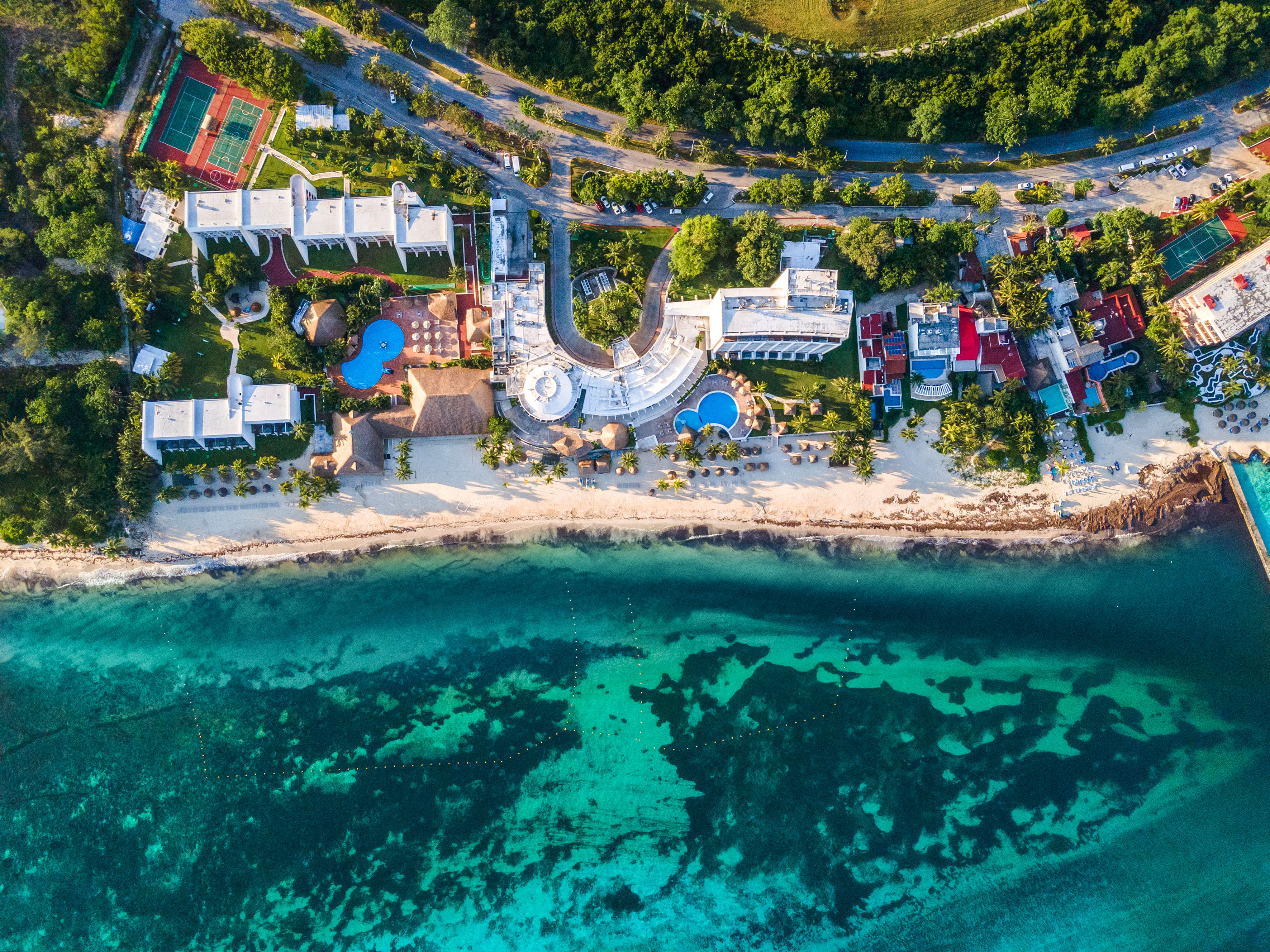 Resort de lujo junto a playa caribeña y mar turquesa, vista aérea.
