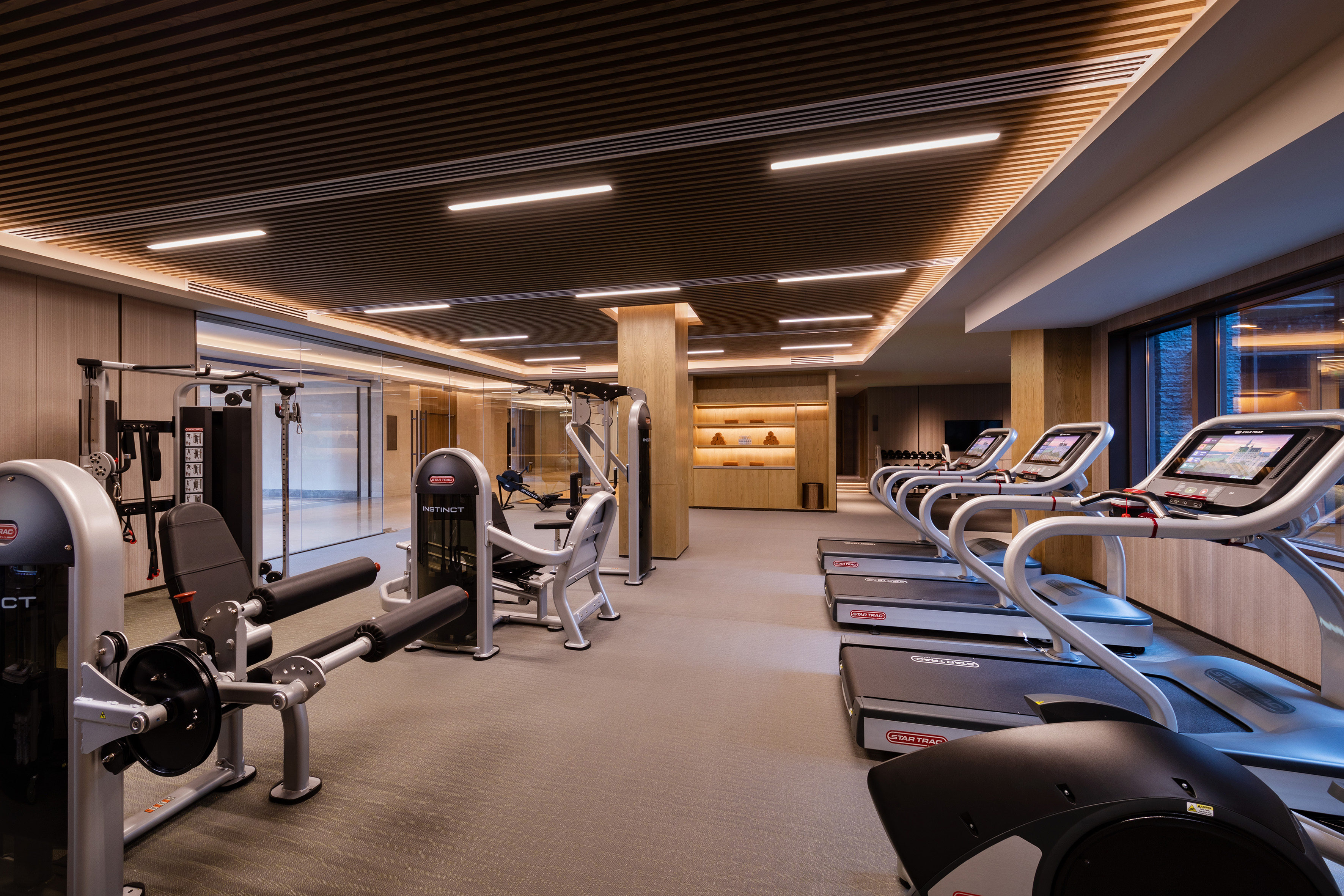Modern gym with treadmills, strength machines, and stylish wood interior.