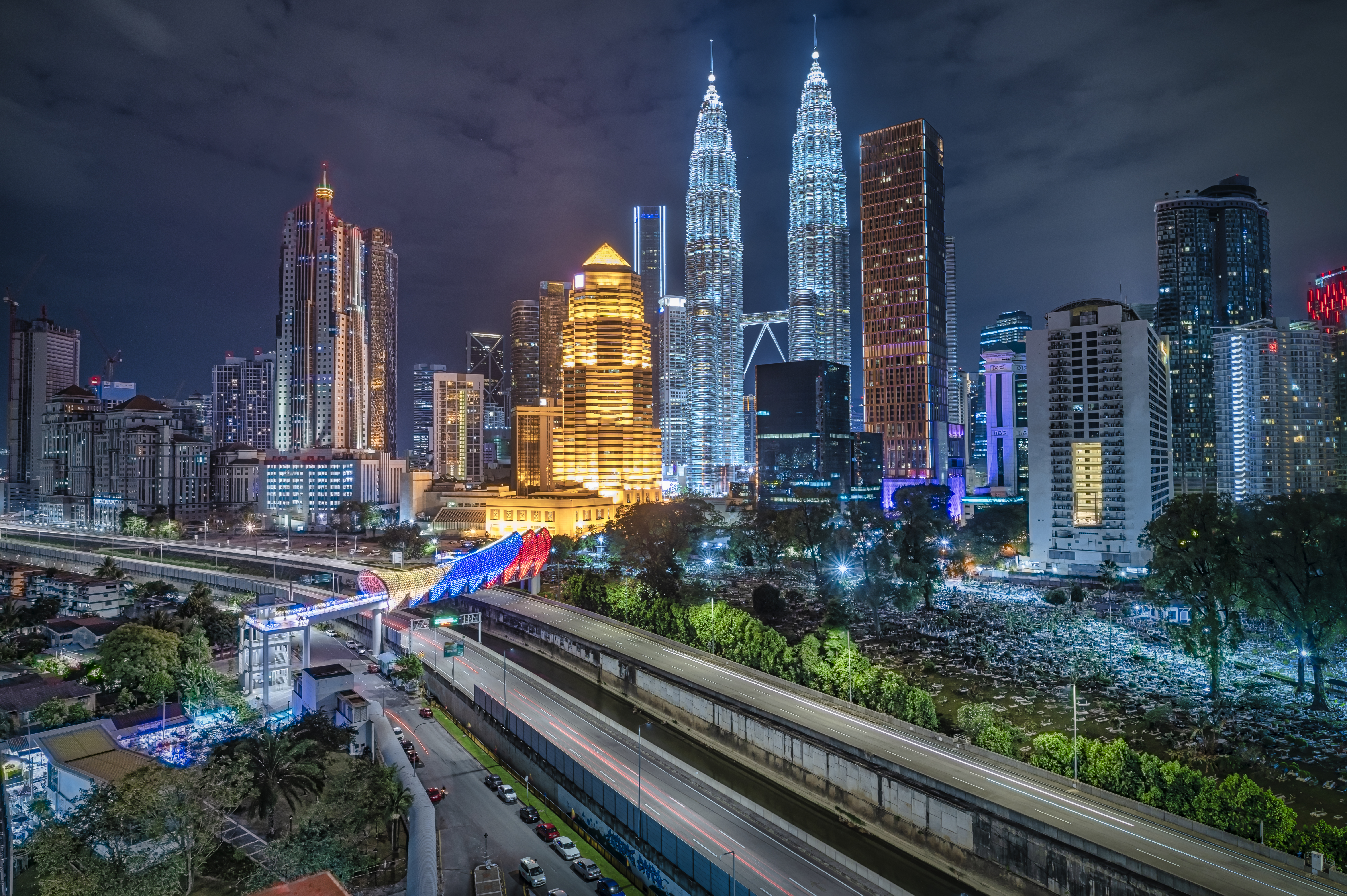 Kuala Lumpur night skyline with Petronas Towers and illuminated highways.