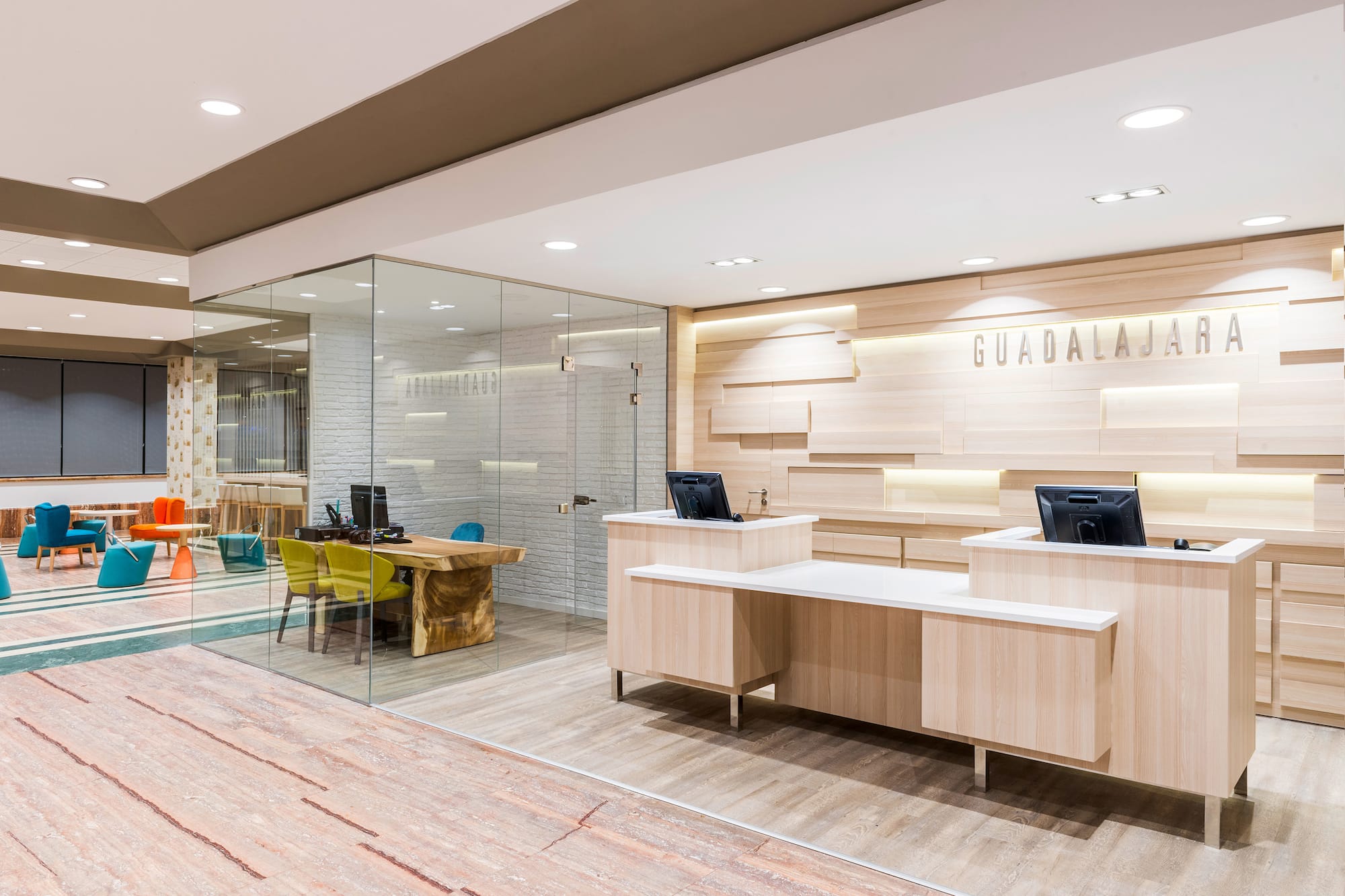 Modern Guadalajara office reception area with wooden desks and glass walls.