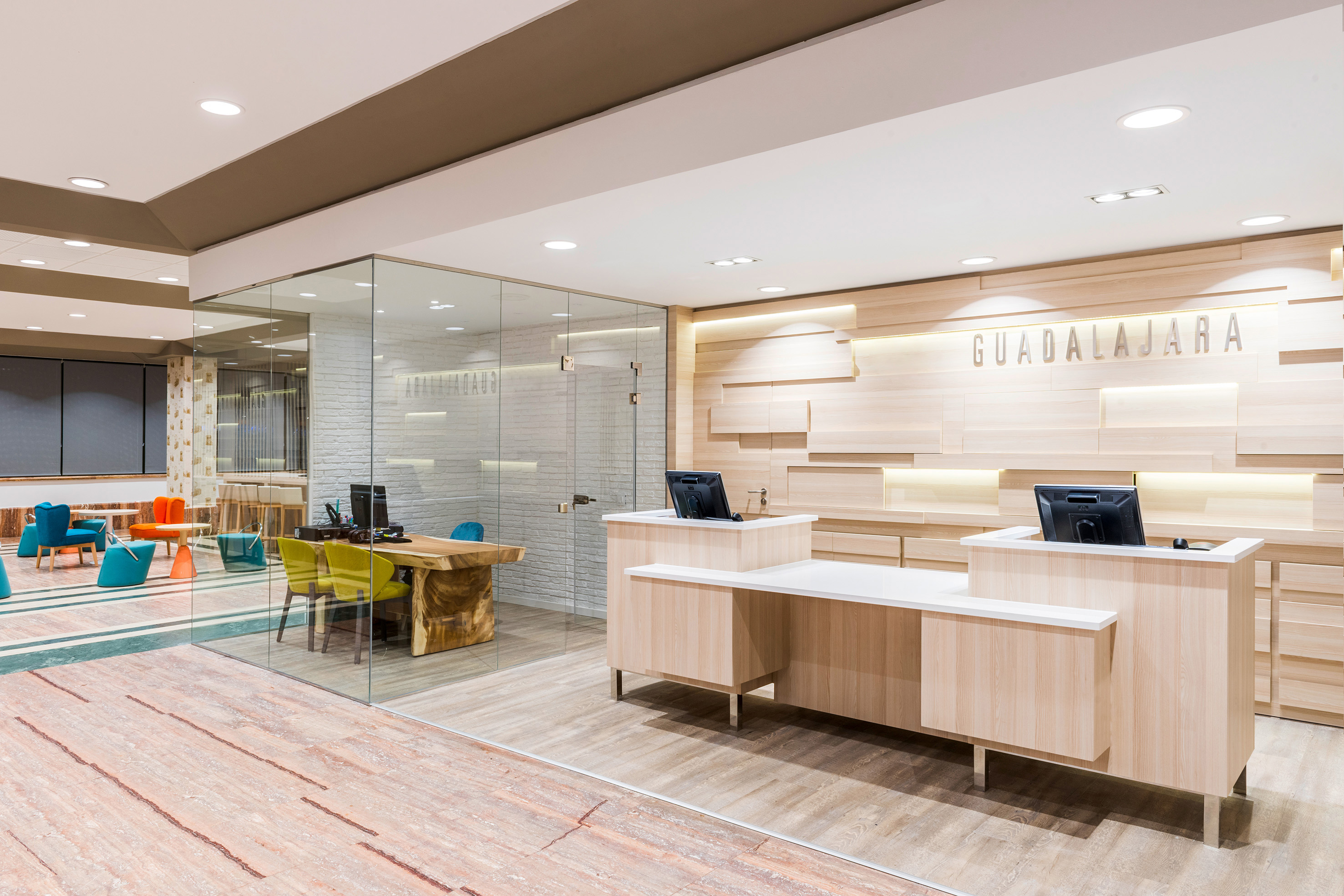 Modern Guadalajara office reception area with wooden desks and glass walls.