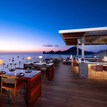 a restaurant with tables and chairs on a deck overlooking the ocean