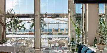 a room with white tables and chairs and a large window