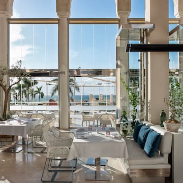 a room with white tables and chairs and a large window