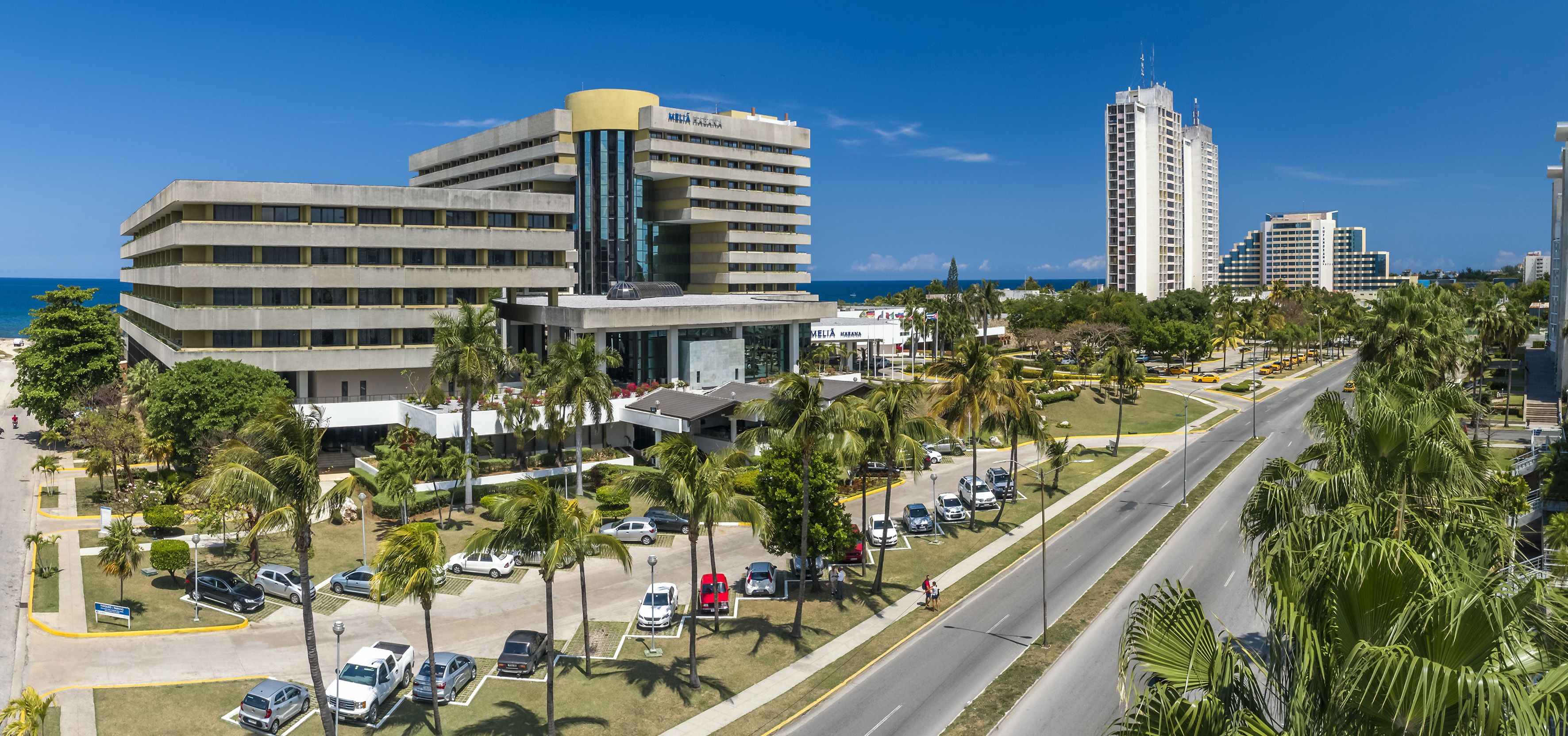 a large building with palm trees and a road