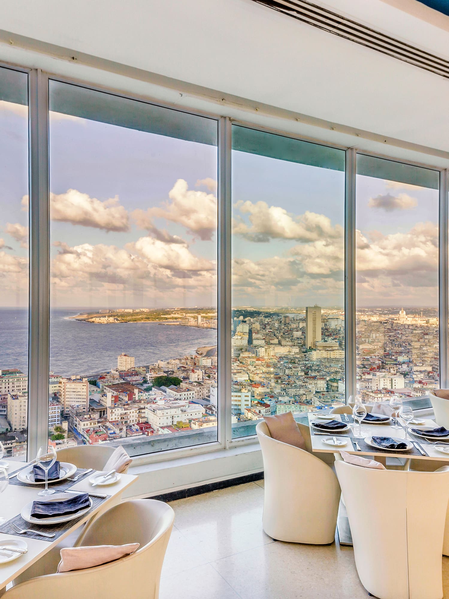 a room with large windows and tables and chairs