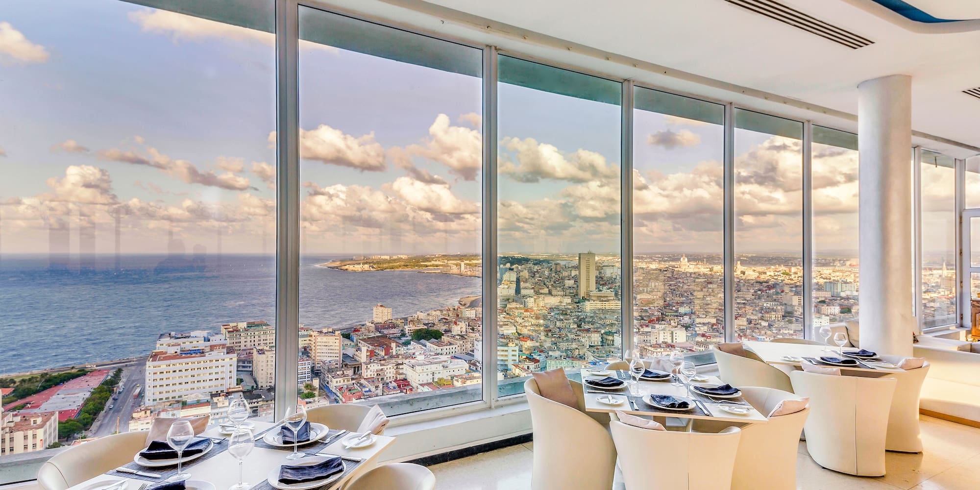 a room with large windows and tables and chairs